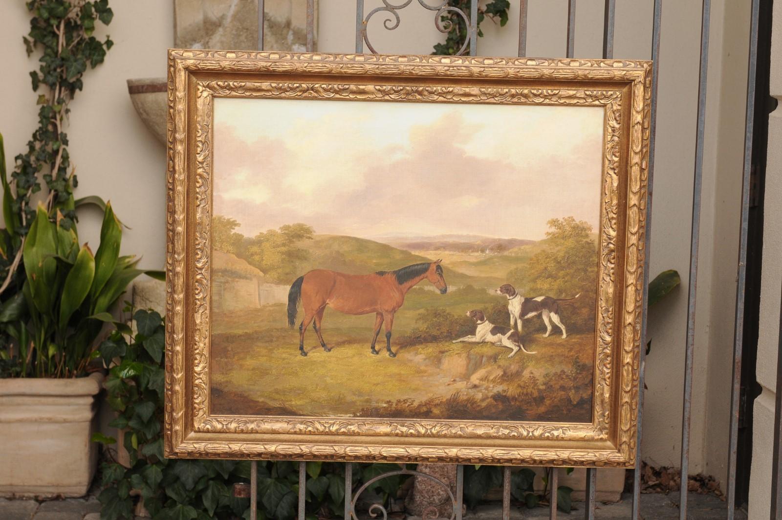 An English Victorian era oil on canvas painting from the mid-19th century, by Thomas Bretland (1802-1874), depicting a horse and two dogs, set in a giltwood frame. Created by naïve painter Thomas W. Bretland in 1852, this oil on canvas painting