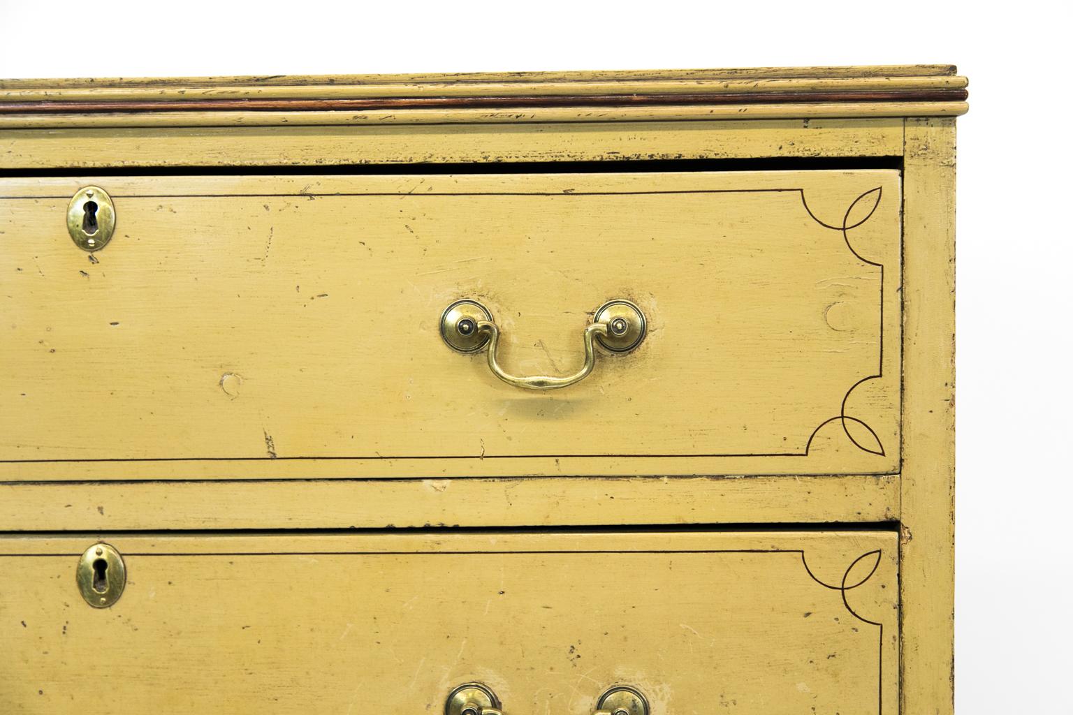 English three-drawer painted chest is done in a plantain color. The top, sides, feet, and drawer fronts have painted line inlay. The apron is shaped on the fronts and sides.