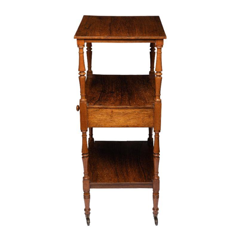 An exceptionally fine Sheraton three tier dumb waiter with center shelf drawer in Brazilian rosewood. The drawer retains its turned rosewood pulls. The turned legs have blocked dies encompassing each shelf and apron, with turned legs that terminate