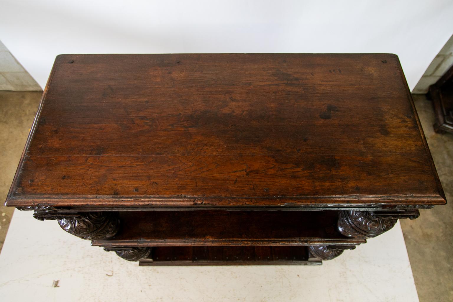 English three tiered court server, with the top and middle aprons having typical Jacobean carved motifs. There are four large bulbous carved shelf supports. The lower shelf has exposed rose head nail construction on all four sides. There is exposed