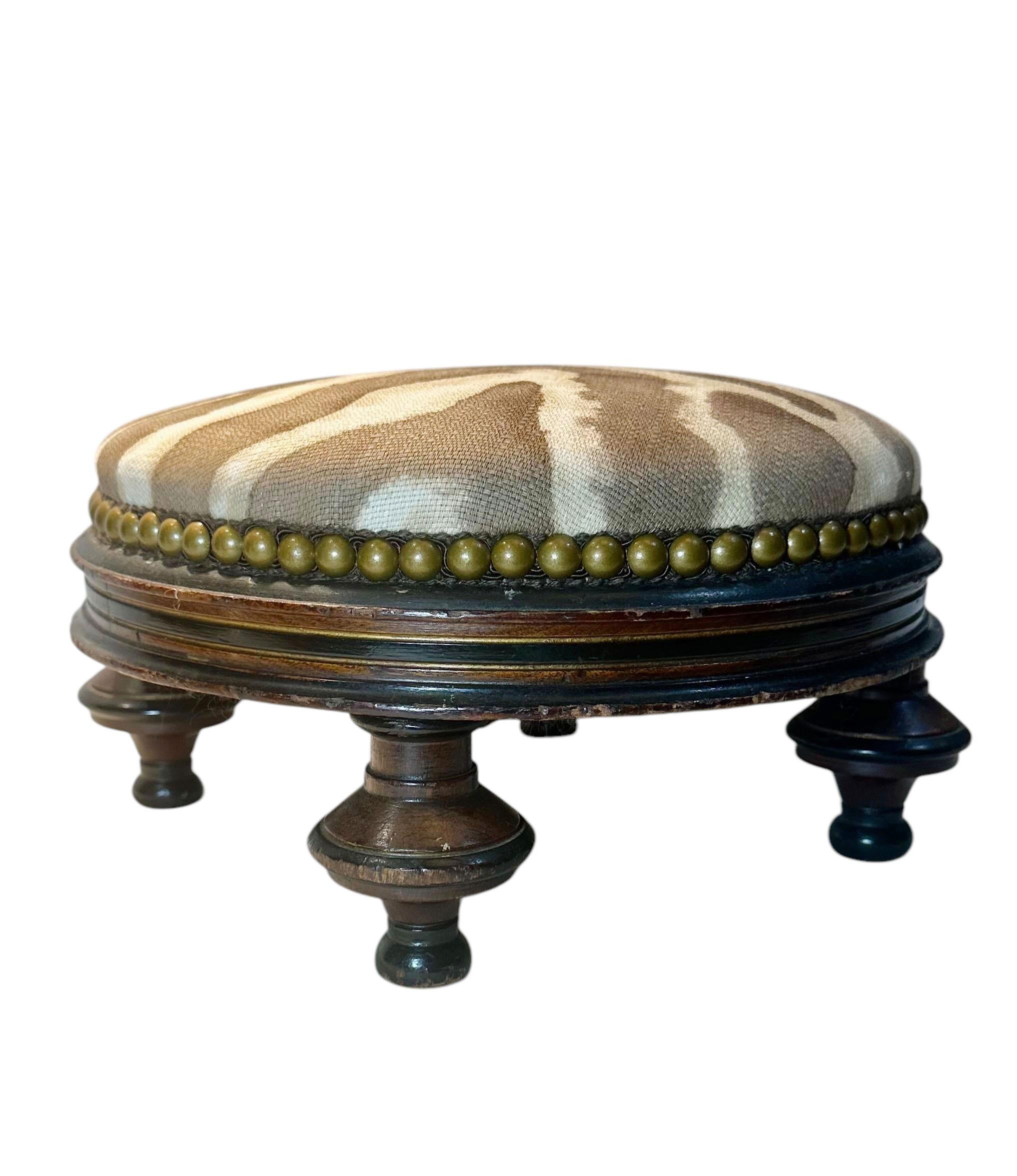 Escabel de madera del siglo XIX, procedente de Inglaterra, con gran pátina y patas rematadas. Tapizada en tela vintage Clearance House de lino y algodón con estampado de tigre y cabezas de clavos antiguas.