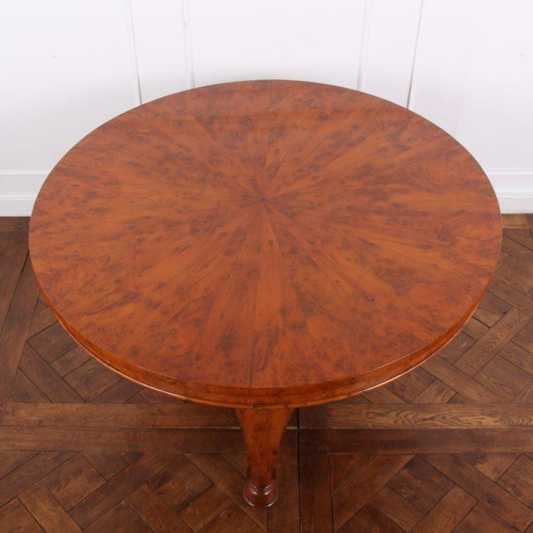 An unusual English early-Victorian breakfast or centre table in yew wood, the triform base with turned feet and inset castors, and supporting a bulbous octagonal-faceted column below radial segmented and veneered top. Circa 1840.



