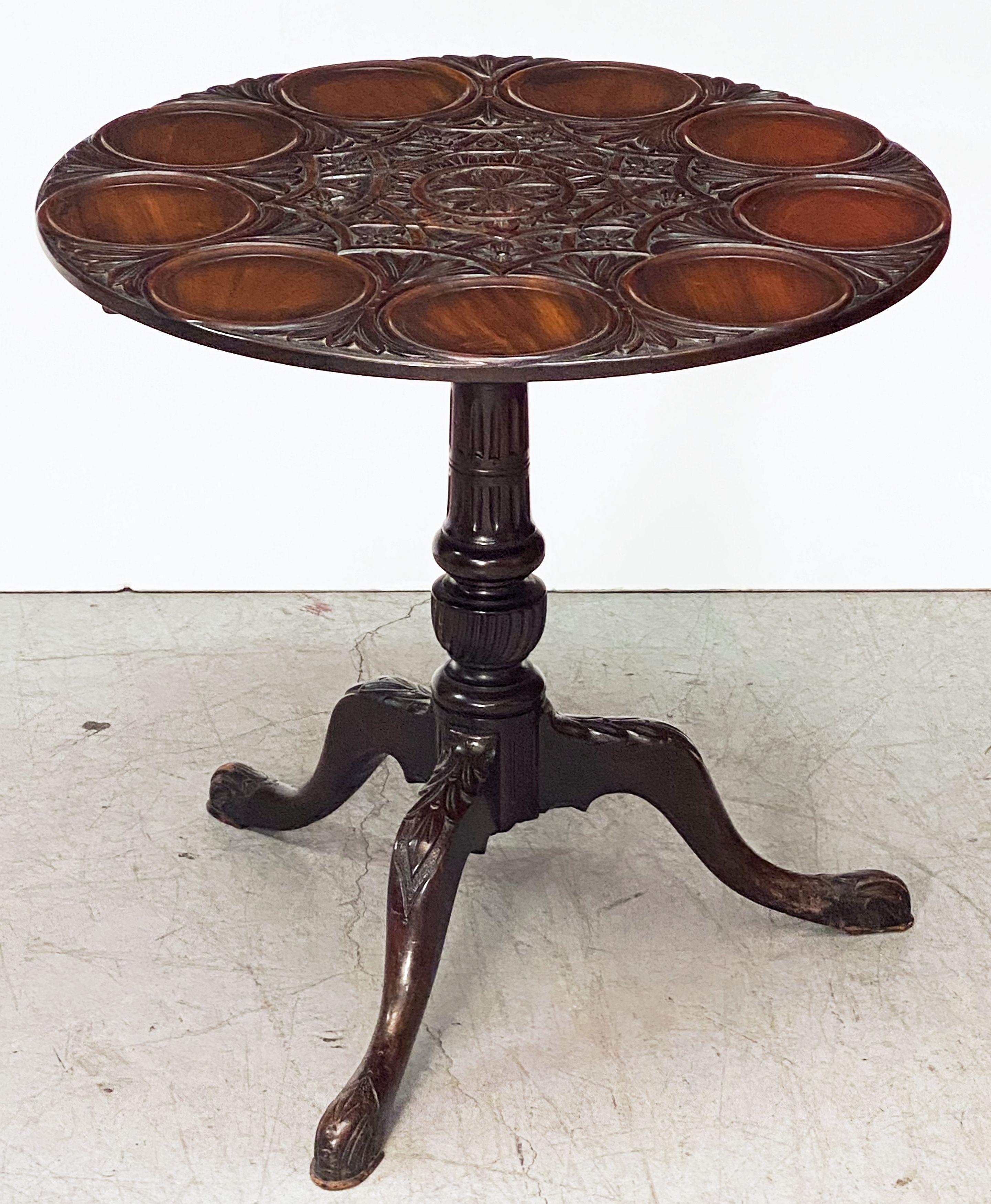 A fine English tilt-top supper or tea table of mahogany, featuring a round or circular top and place-settings for serving plates, over a turned tripod pedestal column support on pad foot legs.
  