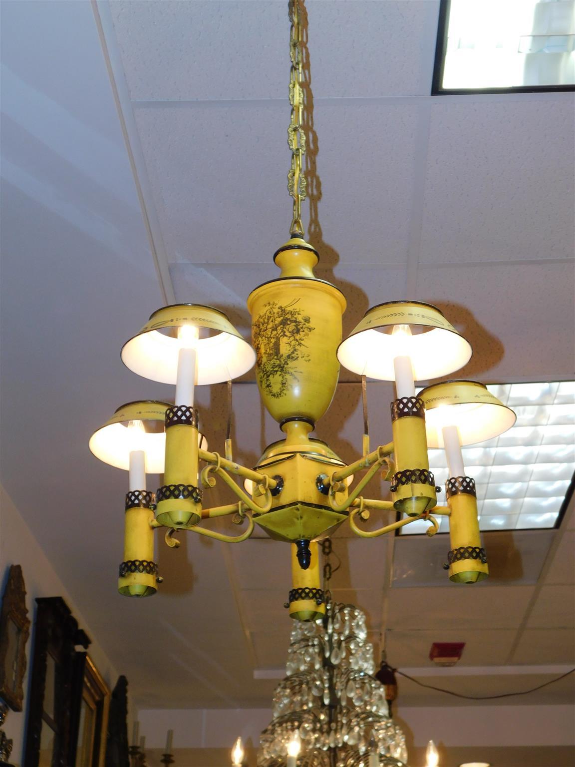 English tole yellow and black paint decorated five light chandelier with central urn foliage fruit basket, acorn finial, and five scrolled arms with the original slot mounted shades. Originally candle powered and has been electrified. Mid 19th