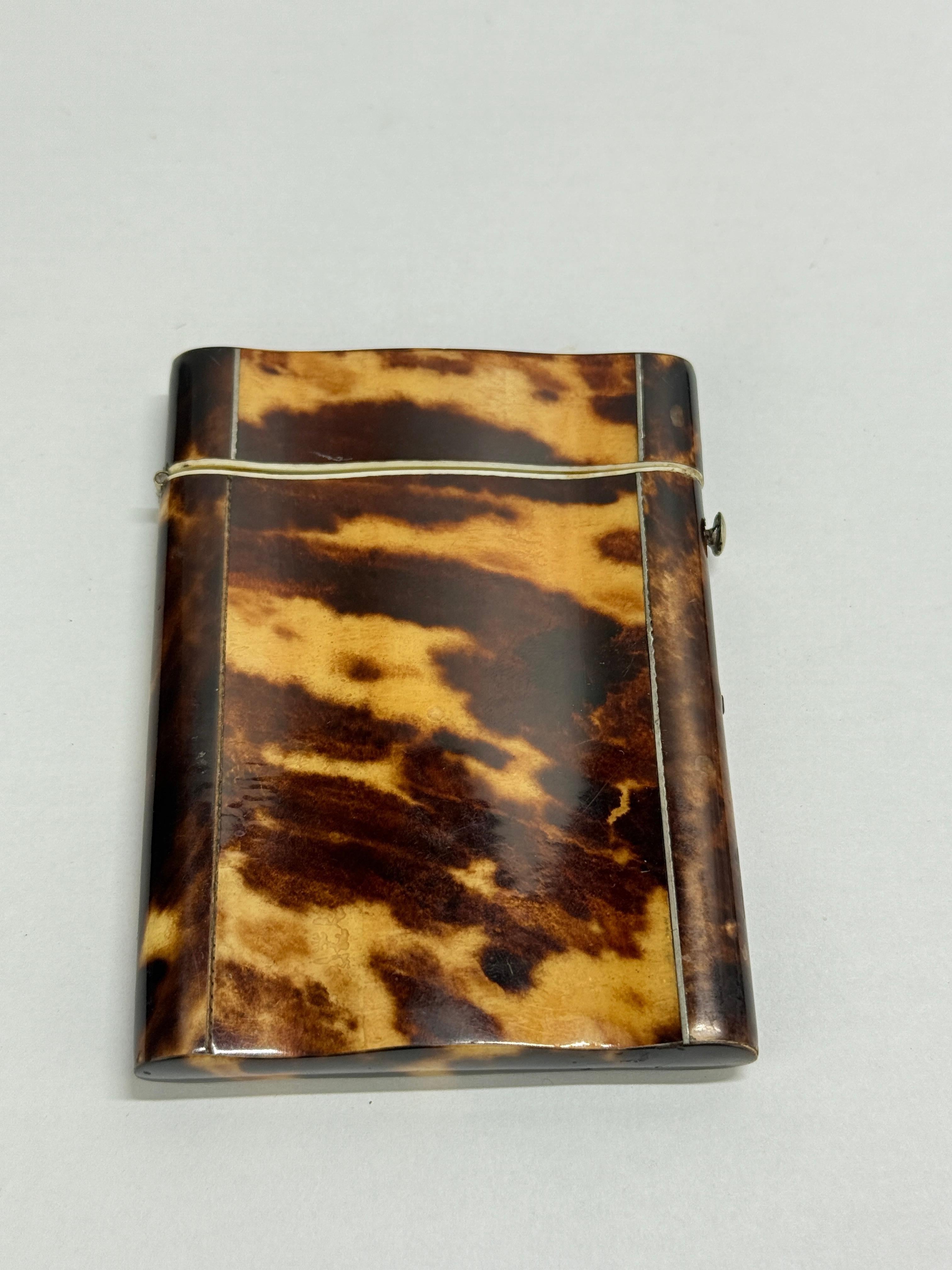 A Georgian-era tortoiseshell card case of refined, minimalist form, circa 1830 or earlier, the surfaces composed of richly patterned shell plates in mottled honey, chestnut, and espresso tones, the figure well-bookmatched and gently domed to the