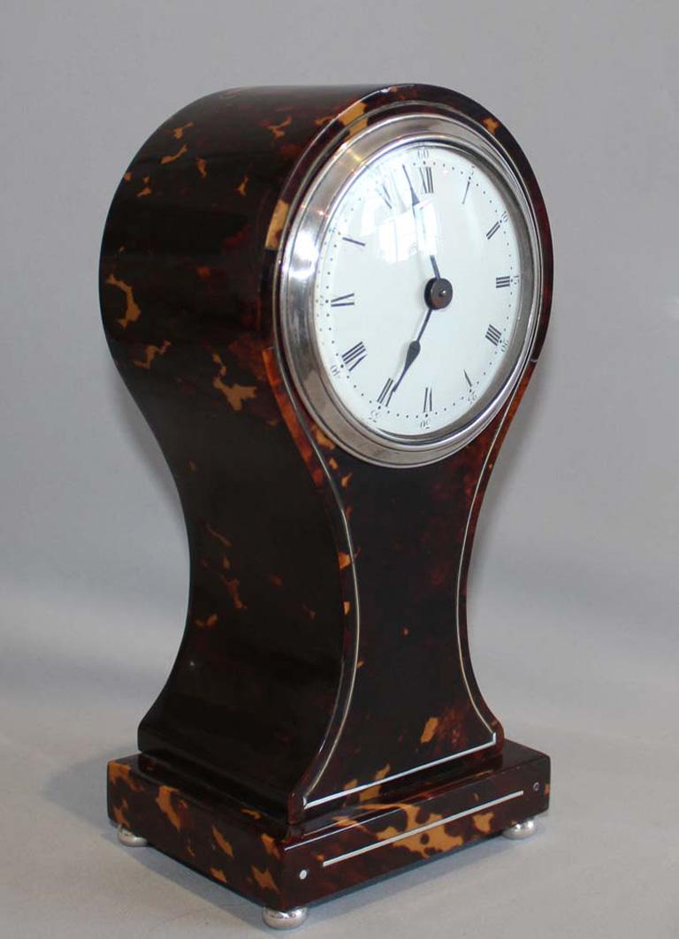 English tortoiseshell and silver strung balloon shaped mantel clock. Excellent condition with fine tortoiseshell on all sides. 8 day movement with platform lever escapement. White enamel convex dial with blued steel spade hands. Roman numeral hour