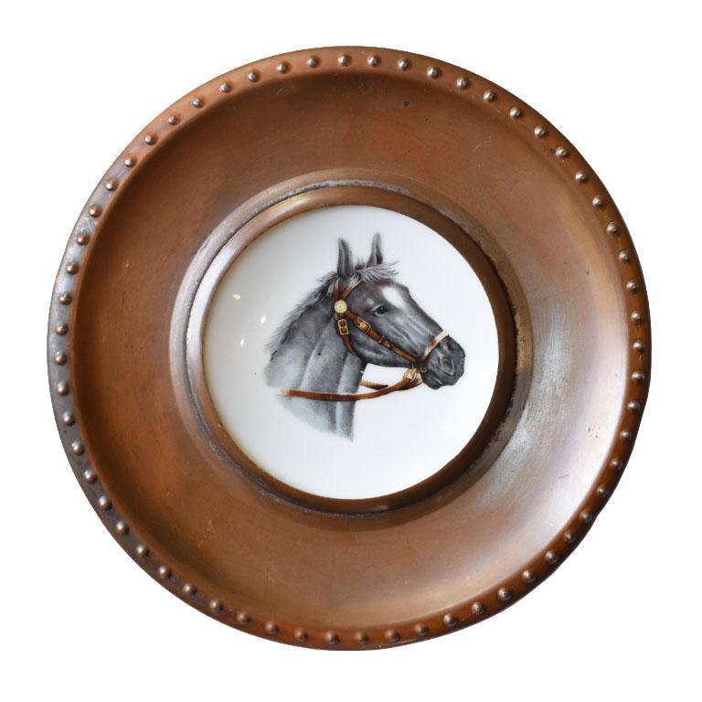 A pair of English Traditional ceramic equestrian horse plates. Each plate is ceramic and features a horse with a bridle at the center. One of the animals is brown, and the other is gray. The plates are framed in a metal federal-style frame with