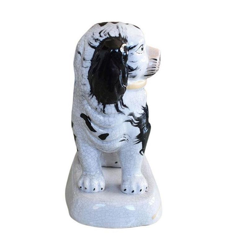 A porcelain King Charles Spaniel ceramic dog in black, white, and gold. A timeless piece spotted on the mantles and bookshelves of collectors across the globe. This piece depicts a sweet pup sitting on its hind legs and wearing a gold