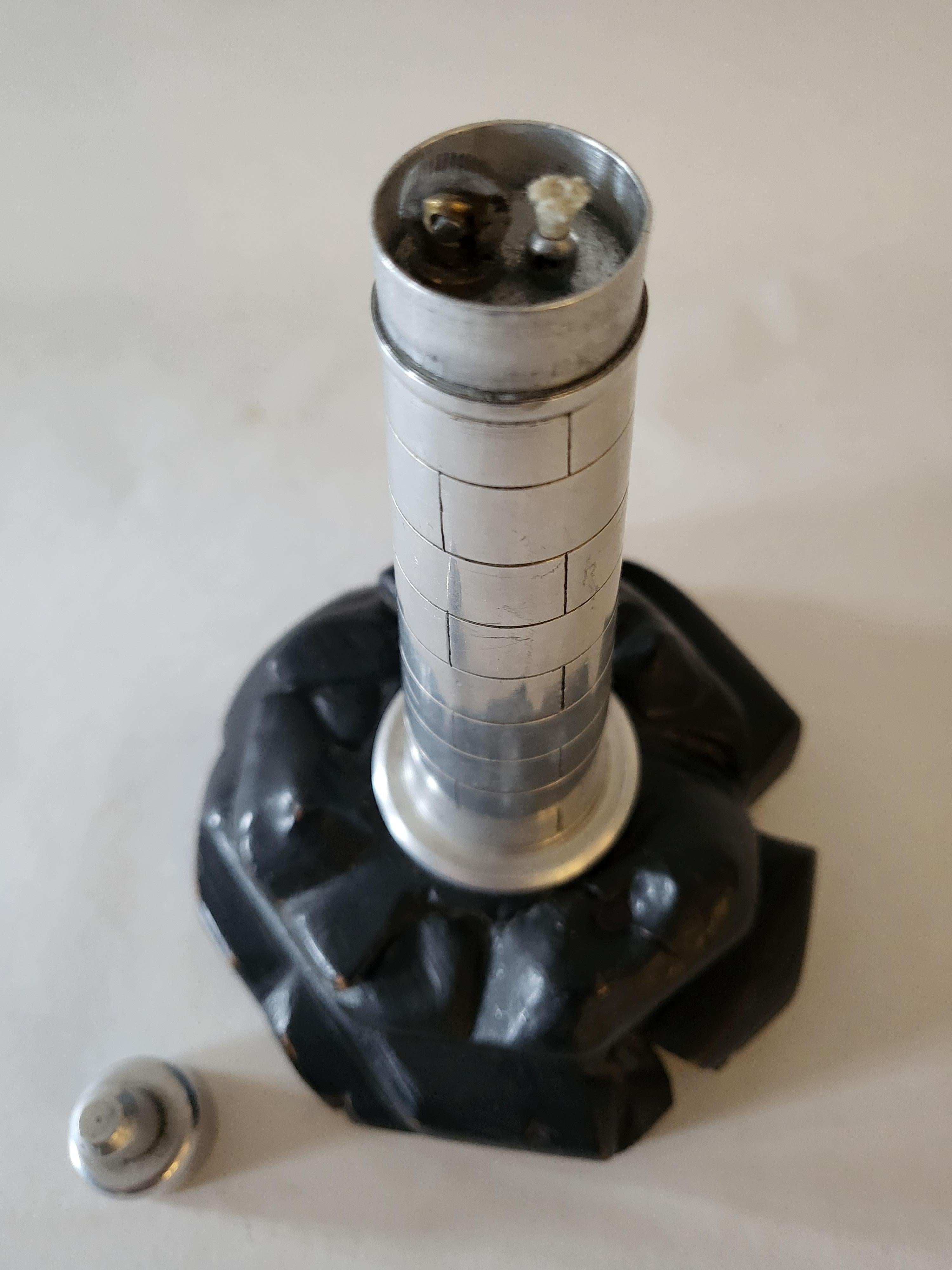 We have listed this wonderful hand made English figurative table lighter as being Trench Art but it was most likely crafted by a tool and die worker in one of the wartime aircraft factories. It features a solid aluminum bodied model of a lighthouse,