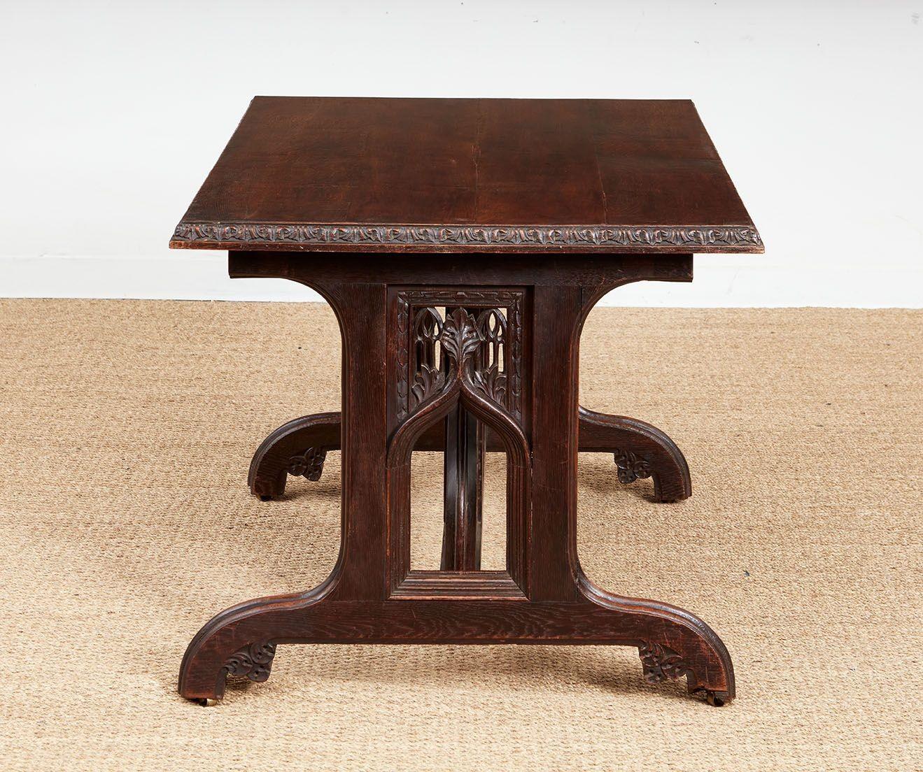 Table centrale en chêne avec un plateau rectangulaire à bord sculpté sur des tréteaux décorés de tracés élaborés et un panneau de support central en forme.  Les pieds sont munis de roulettes en laiton.  Utile comme table d'entrée, de bibliothèque,