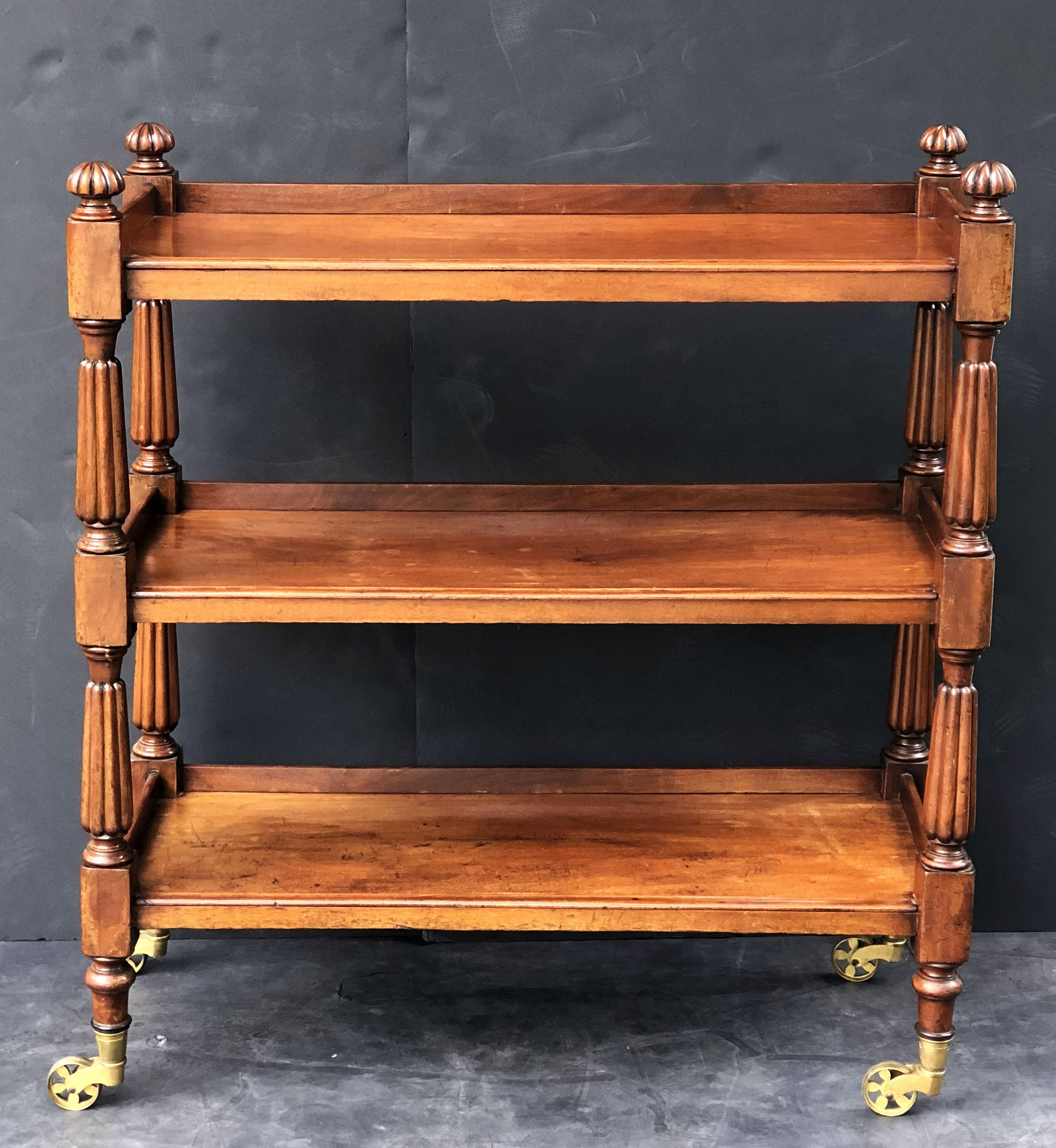 A fine English buffet trolley or console server (or dumb waiter) of mahogany, with William IV styling, featuring three tiers with edge-moulded tops, each with back gallery frieze, each tier adjoined to four turned column supports topped with
