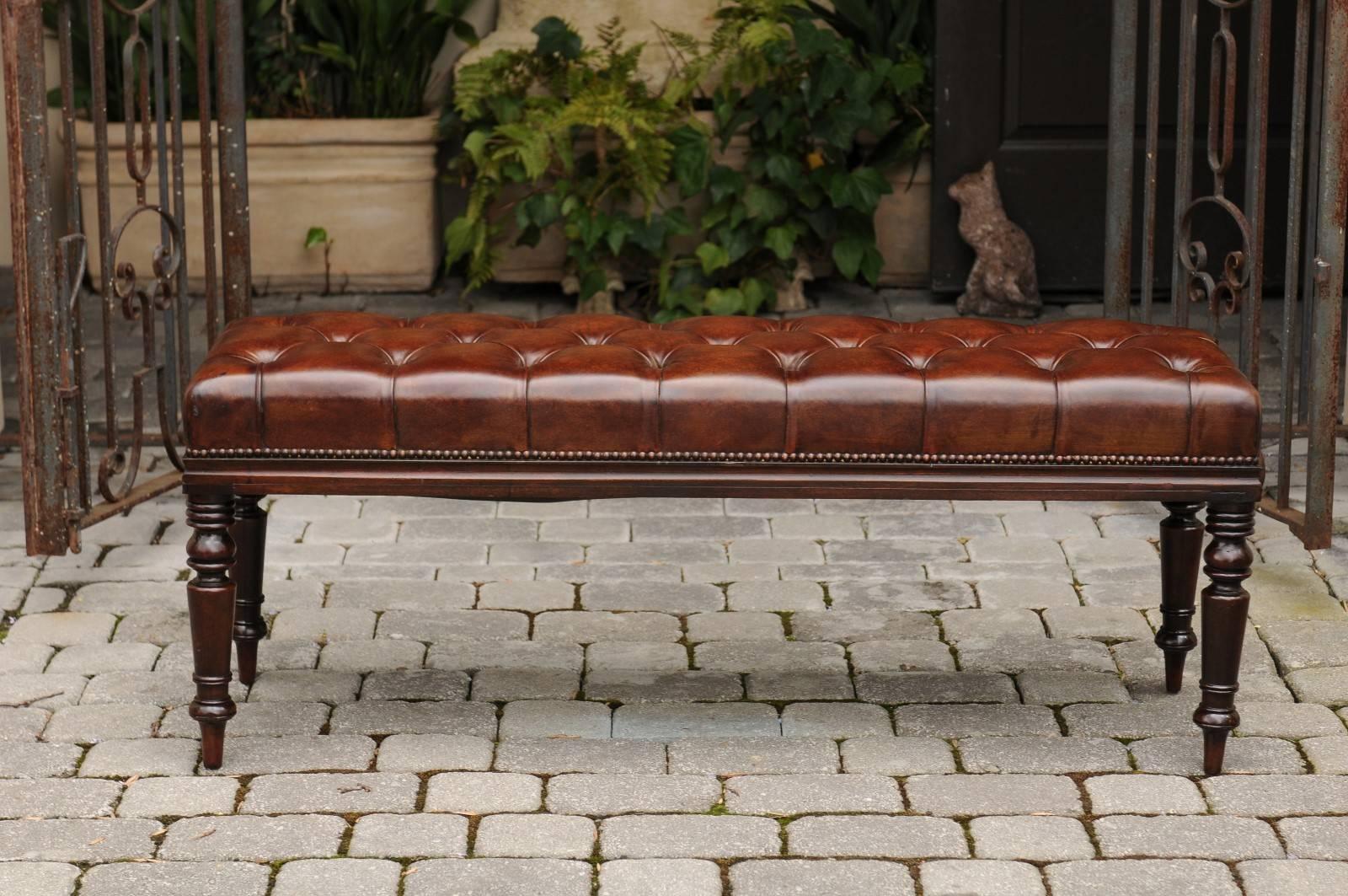 An English tufted leather and mahogany backless bench from the second half of the 19th century. This English bench features a rectangular seat covered with an exquisite tufted leather upholstery, accented by a nailhead trim. The bench is raised on