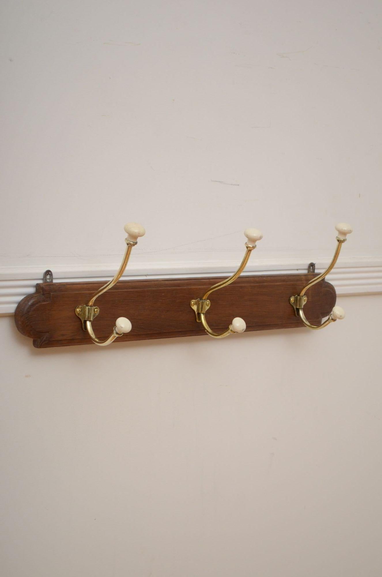 P0262  Stylish turn of the century English coat hooks, having three brass and ceramic hat and coat hooks on oak board. This antique coat rack is in home ready condition, fitted with 2 wall brackets. c1900 UK delivery included.
H8.5