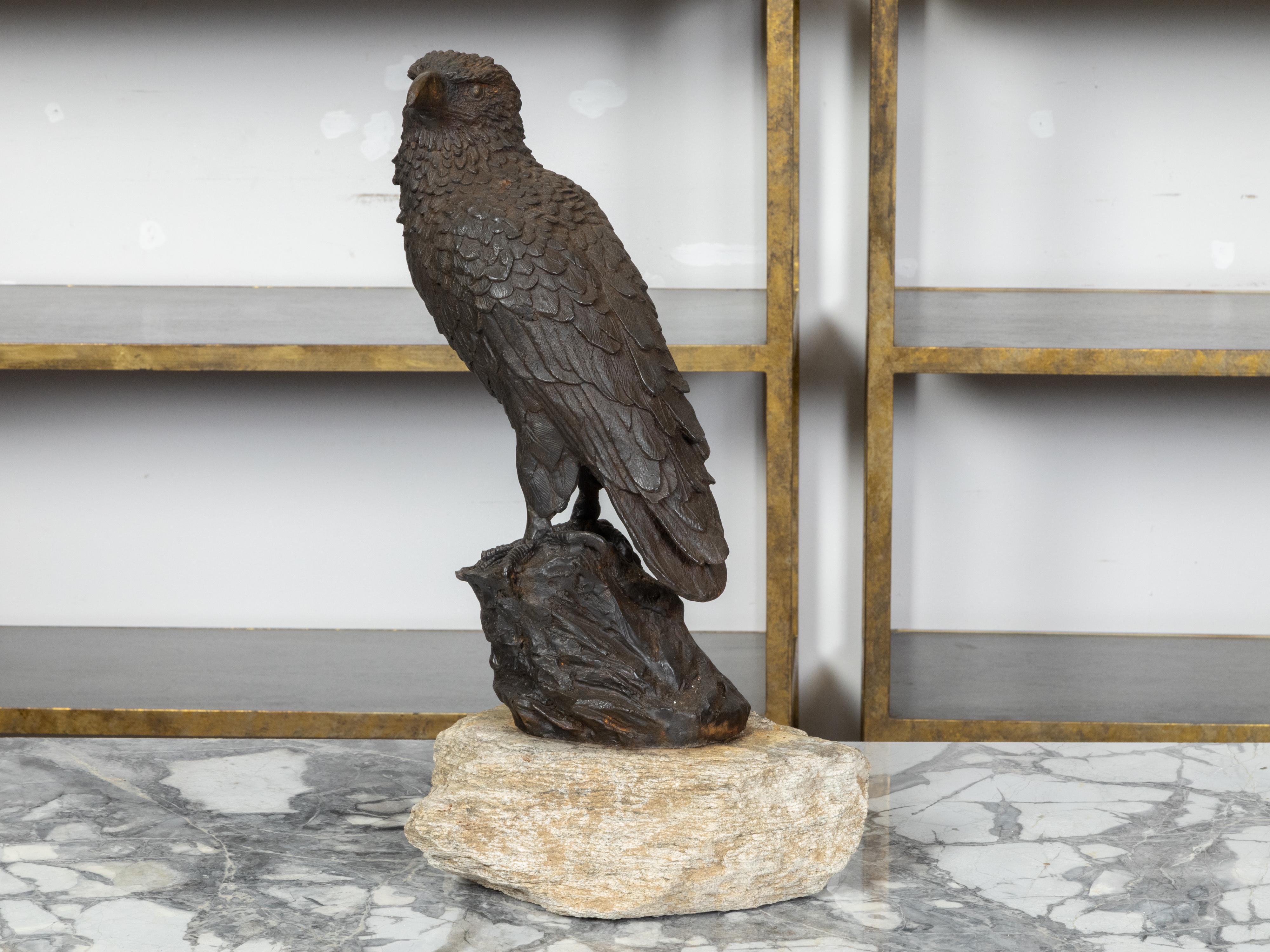 An English iron sculpture from the early 20th century depicting an eagle perched on a rock, with dark brown patina. Created in England during the Turn of the Century which saw the transition between the 19th to the 20th century, this iron sculpture