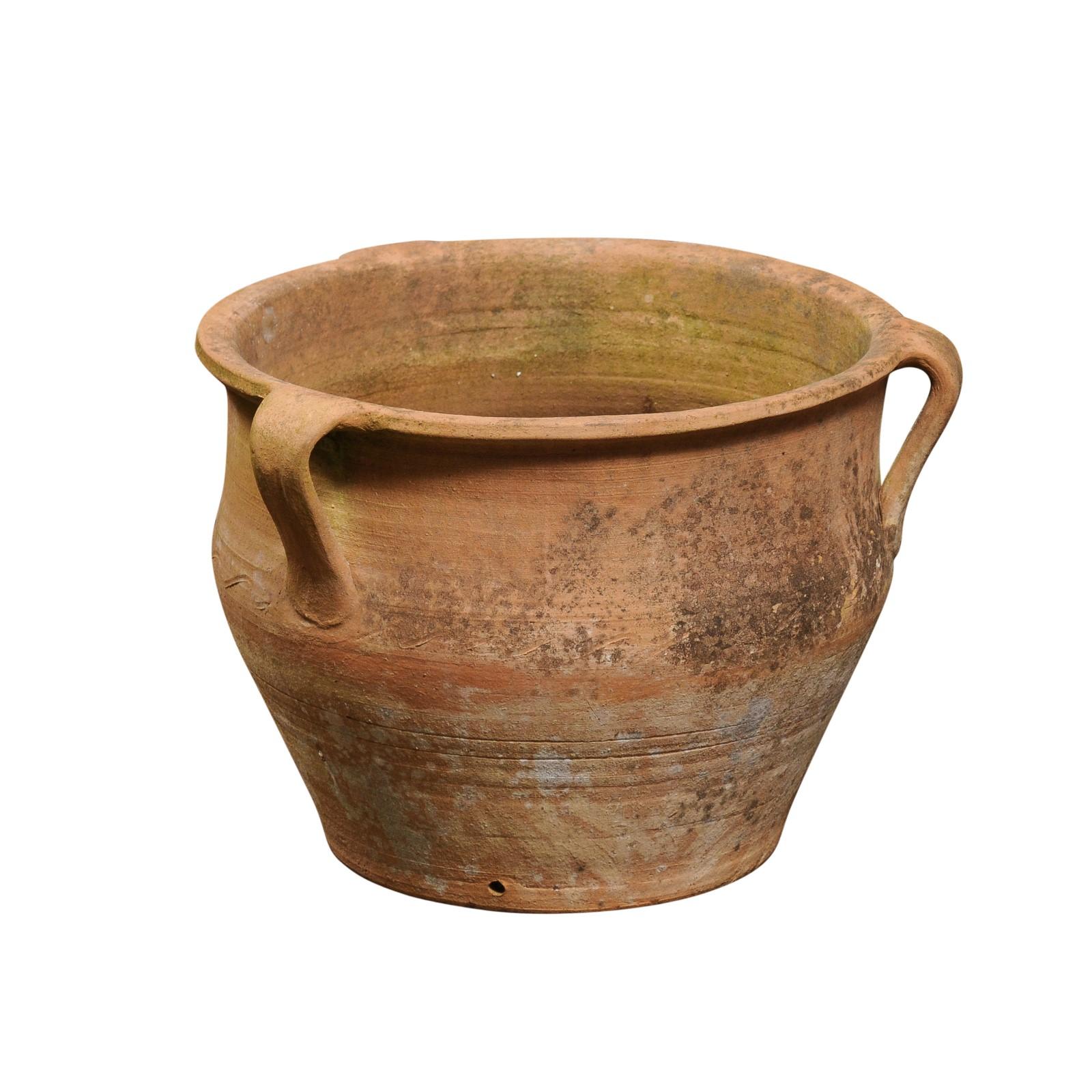 An English Turn of the century terracotta planter from the early 20th century, with three handles, wavy motifs and weathered patina. Created in England during the 20th century, this terracotta planter charms us with its generous round silhouette