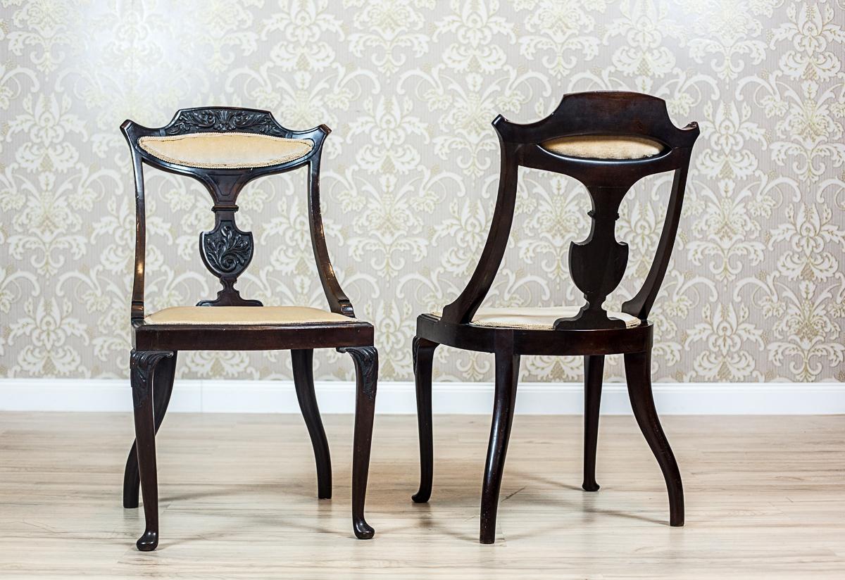 We present you two chairs with slightly bent frontal legs, and slightly prominent knees that are ornamented with a woodcarving. 
The seats and a part of the back splats are upholstered. 
Furthermore, the backrests have side rails which start in