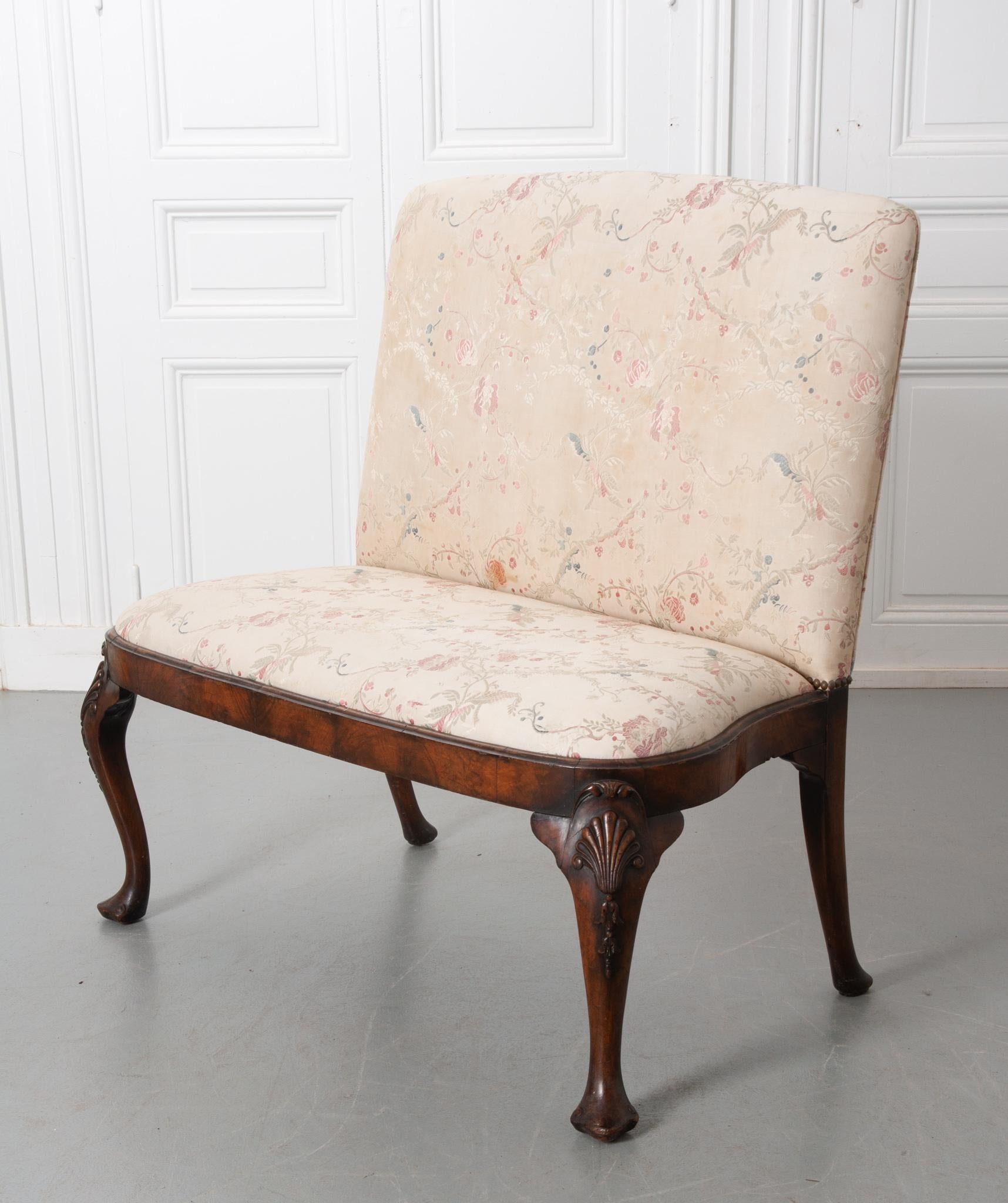 A beautiful antique chippendale upholstered bench from England! The fabric is in good antique condition for its age with slight staining that does not take away from the overall quality. Floral patterns in blue, pink, and green thread add a