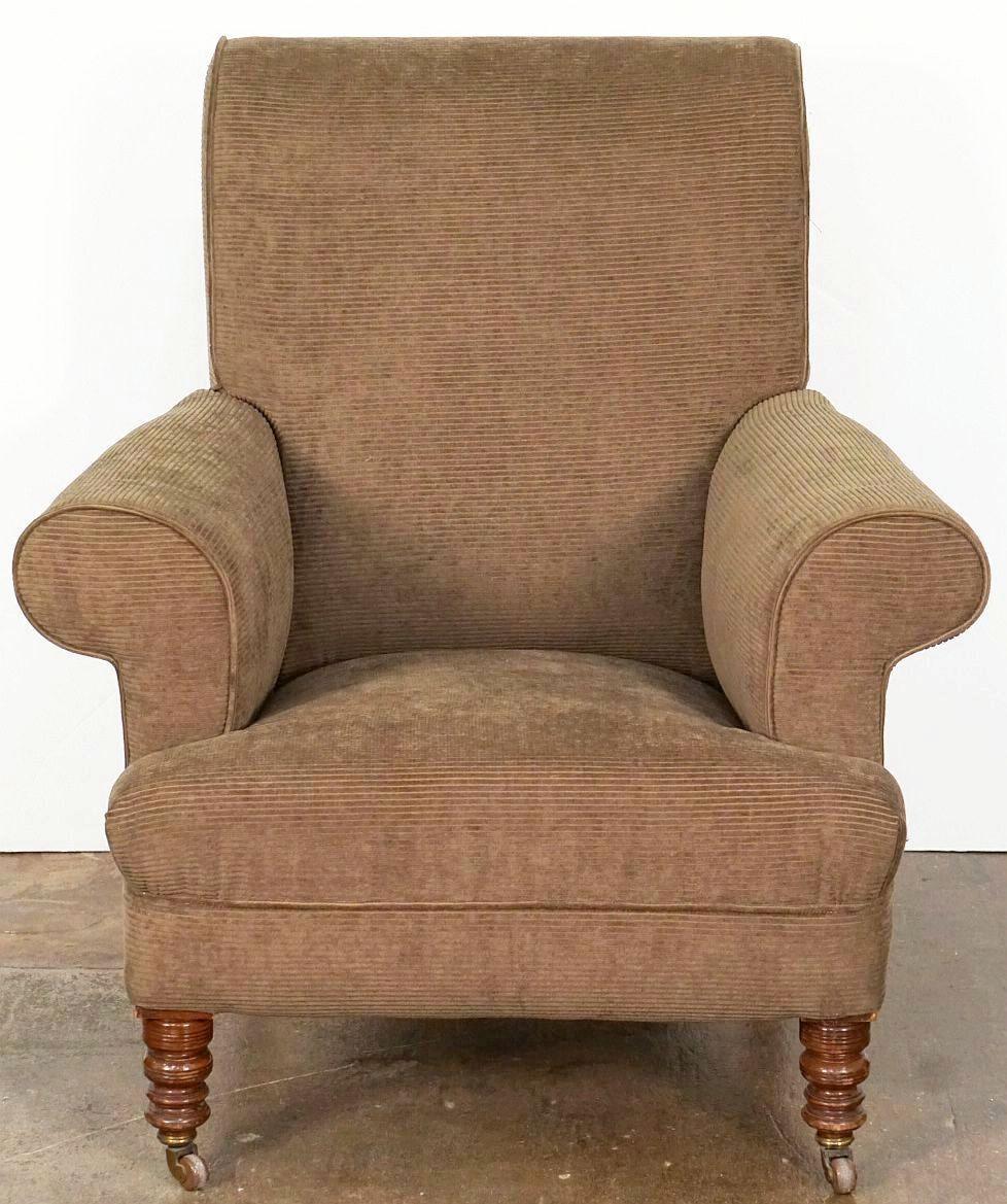 A large handsome English wingback lounge or fireside library chair from the Edwardian era, featuring recently upholstered back and arms, with a comfortable fixed pillow seat, on turned wood legs with rolling casters.

Measures: Seat H 16 1/2 inches