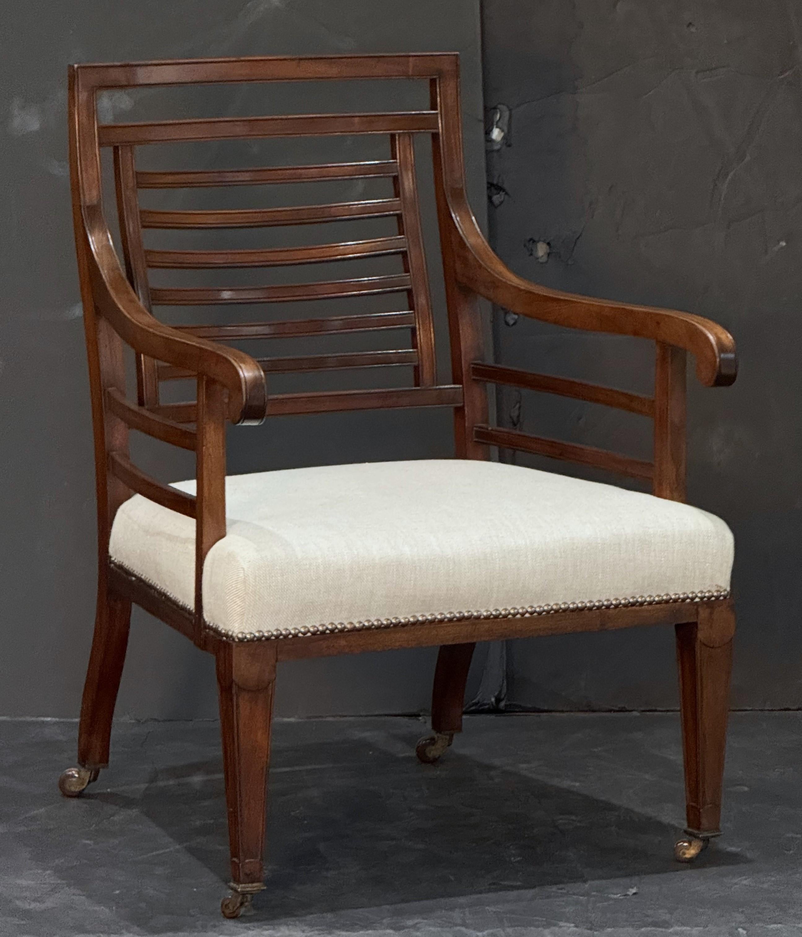 A fine period Georgian vernacular reading chair from England, circa 1820,  featuring an elegant frame with a comfortable upholstered seat. 
The horizontal slats to the back are united by two vertical rails forming a small square design, set within a