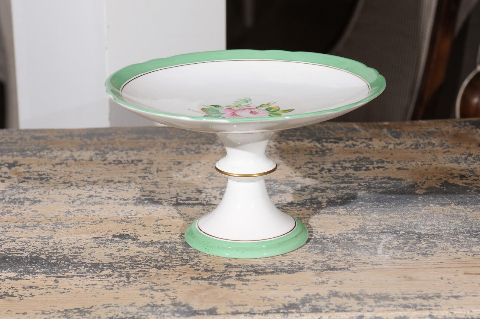 An English Victorian botanical compote from the late 19th century, with pink roses, green and gold trim and hourglass-shaped base. Born in England during Queen Victoria's later years, this charming compote features a delicate central rose surrounded