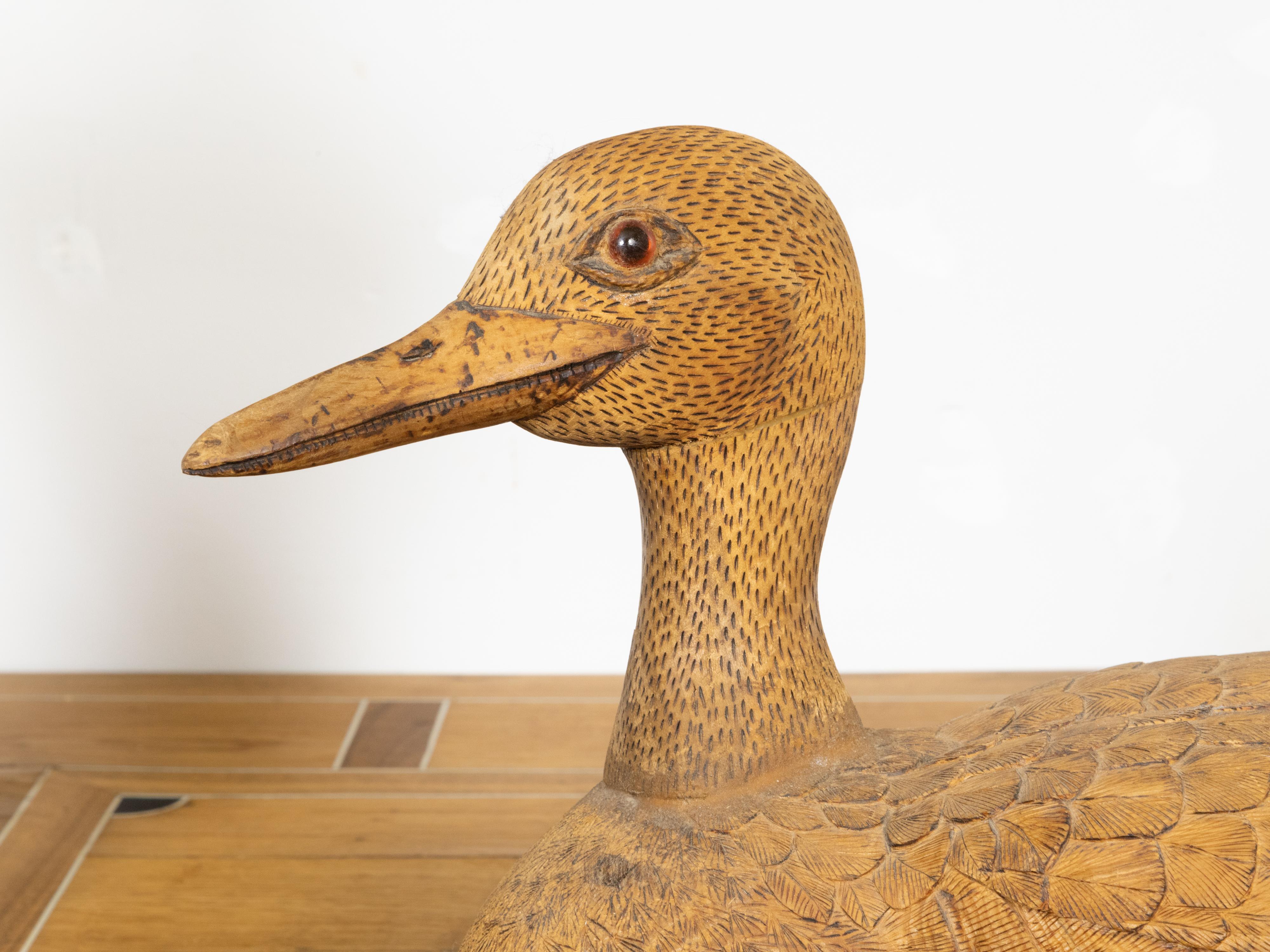 An English Victorian period carved wooden duck sculpture from the 19th century with nicely detailed plumage and brown eyes. Step back into the quaint charm of the Victorian era with this beautifully crafted English wooden duck from the 19th century,
