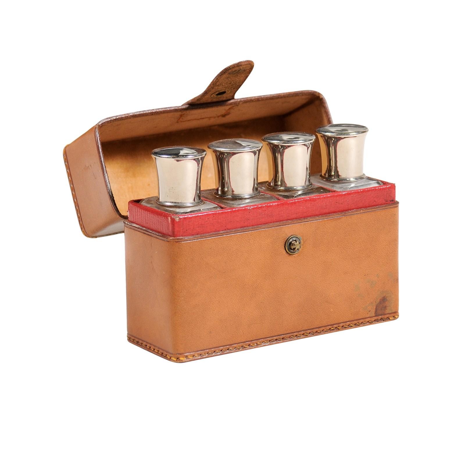 An antique English Victorian period light brown leather toiletry travel set from the late 19th century with four clear glass bottles and in-curving silver lids. Created in England during the later years of Queen Victoria's reign in the 19th century,