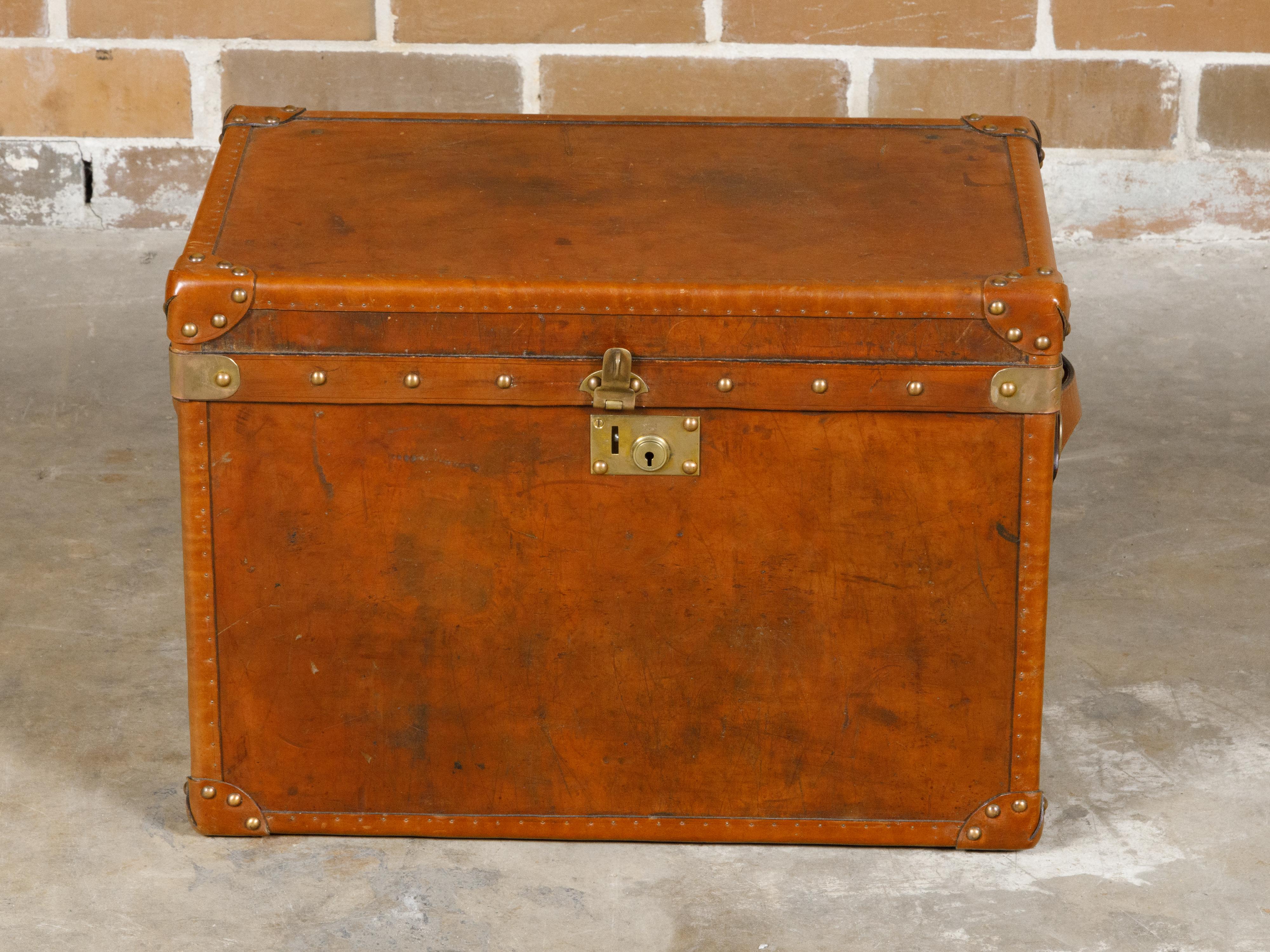 An English Victorian period brown leather trunk from the 19th century with brass accents and lateral handles. This 19th-century English Victorian brown leather trunk embodies the elegance and robustness of its era, adorned with brass accents that