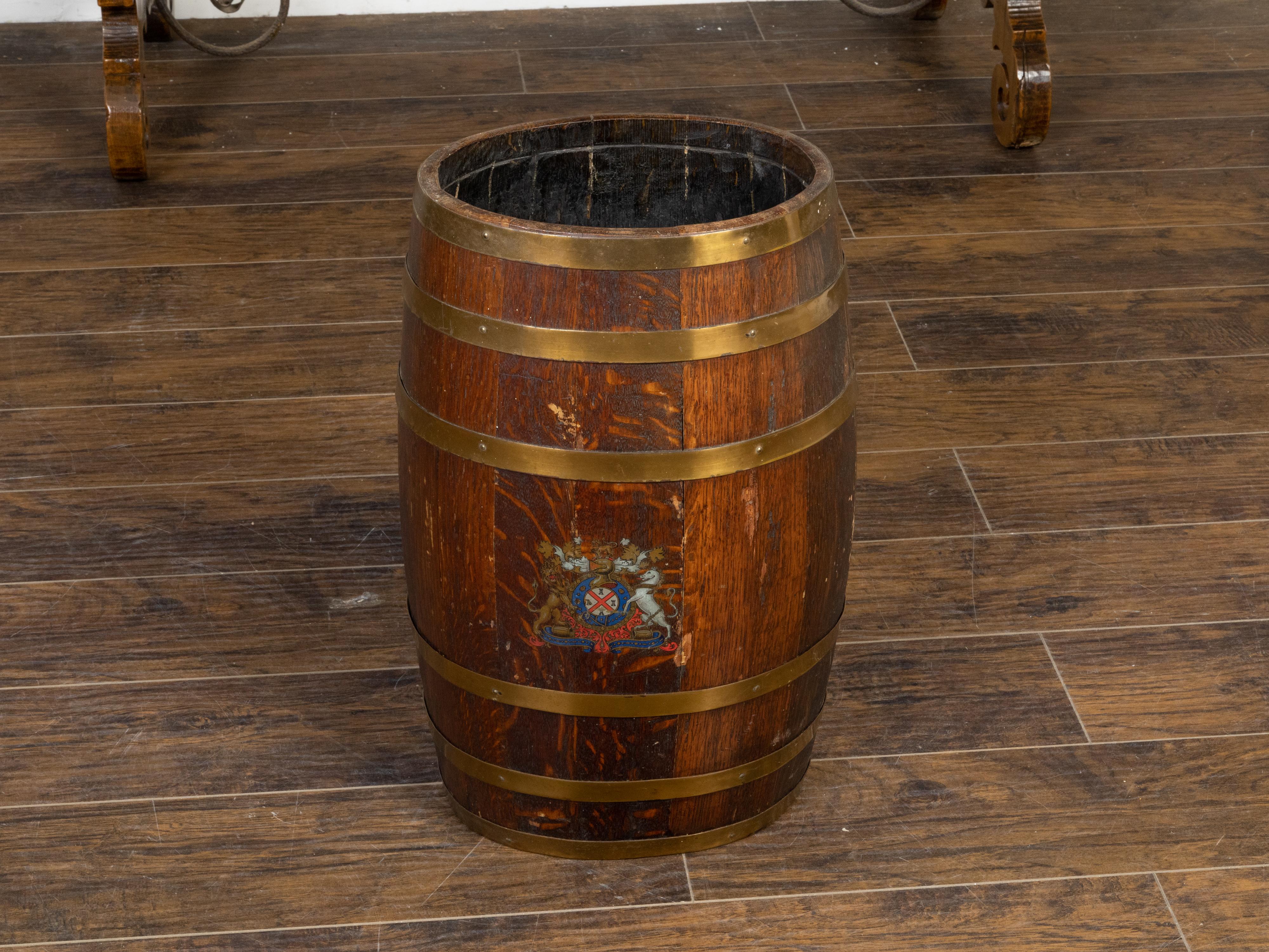 An English Victorian period wooden oval shaped barrel from the 19th century with painted coat of arms and brass braces. Step into the grandeur of the Victorian era with this English wooden barrel from the 19th century, a piece that beautifully