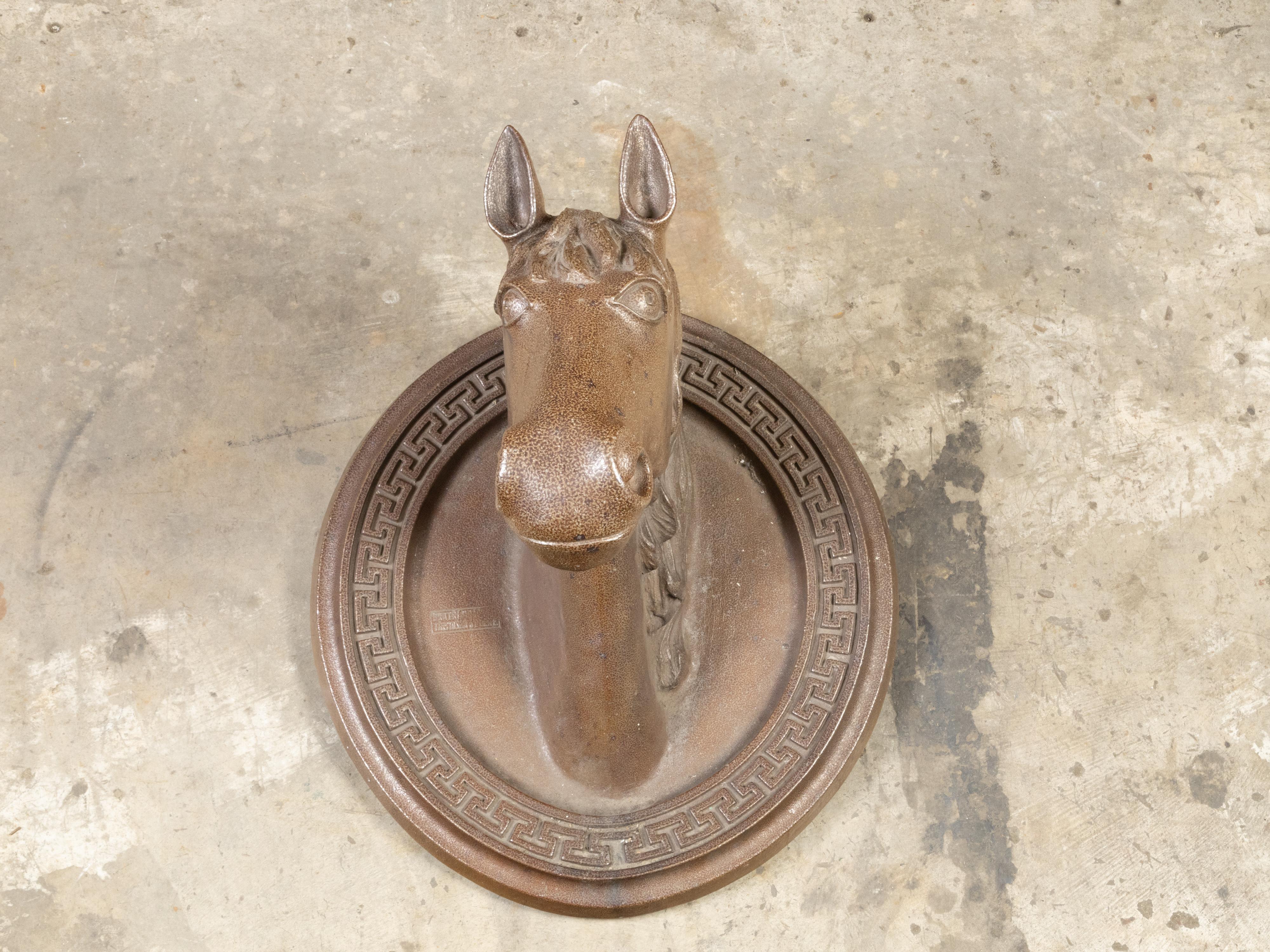 An English Victorian period terracotta horse head sculpture from the 19th century on oval backplate with Greek Key motifs. Created in England during the reign of Queen Victoria in the 19th century, this terracotta wall mounted sculpture depicts a