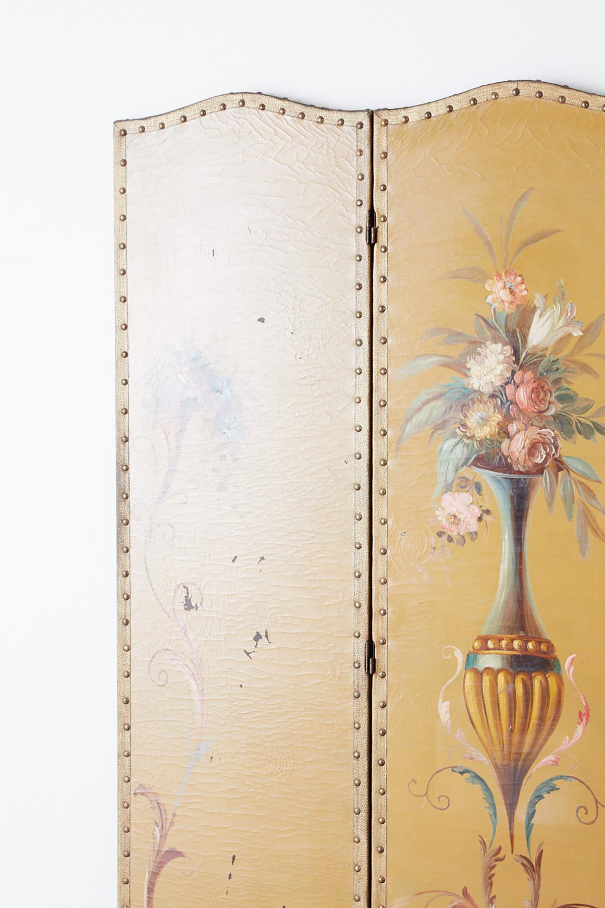 Enchanting English Victorian era three-panel painted folding floor screen. Made in the Adams style featuring a large Roman vase decorated with colorful flowers and arabesque vine scrolls. The dressing screen has a wooden frame covered with canvas