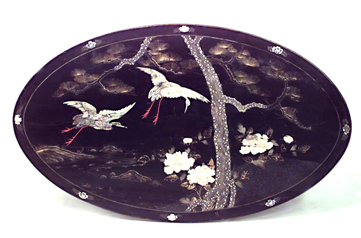 English Victorian black lacquered and pearl inlaid oval center table with gilt pedestal base and herons and floral decoration.
