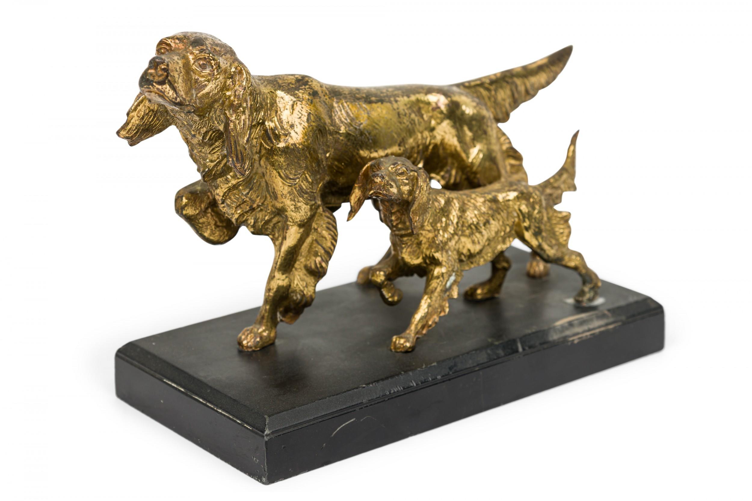 English Victorian-style group of two brass spaniel dogs mid-stride atop a rectangular black cast iron base.