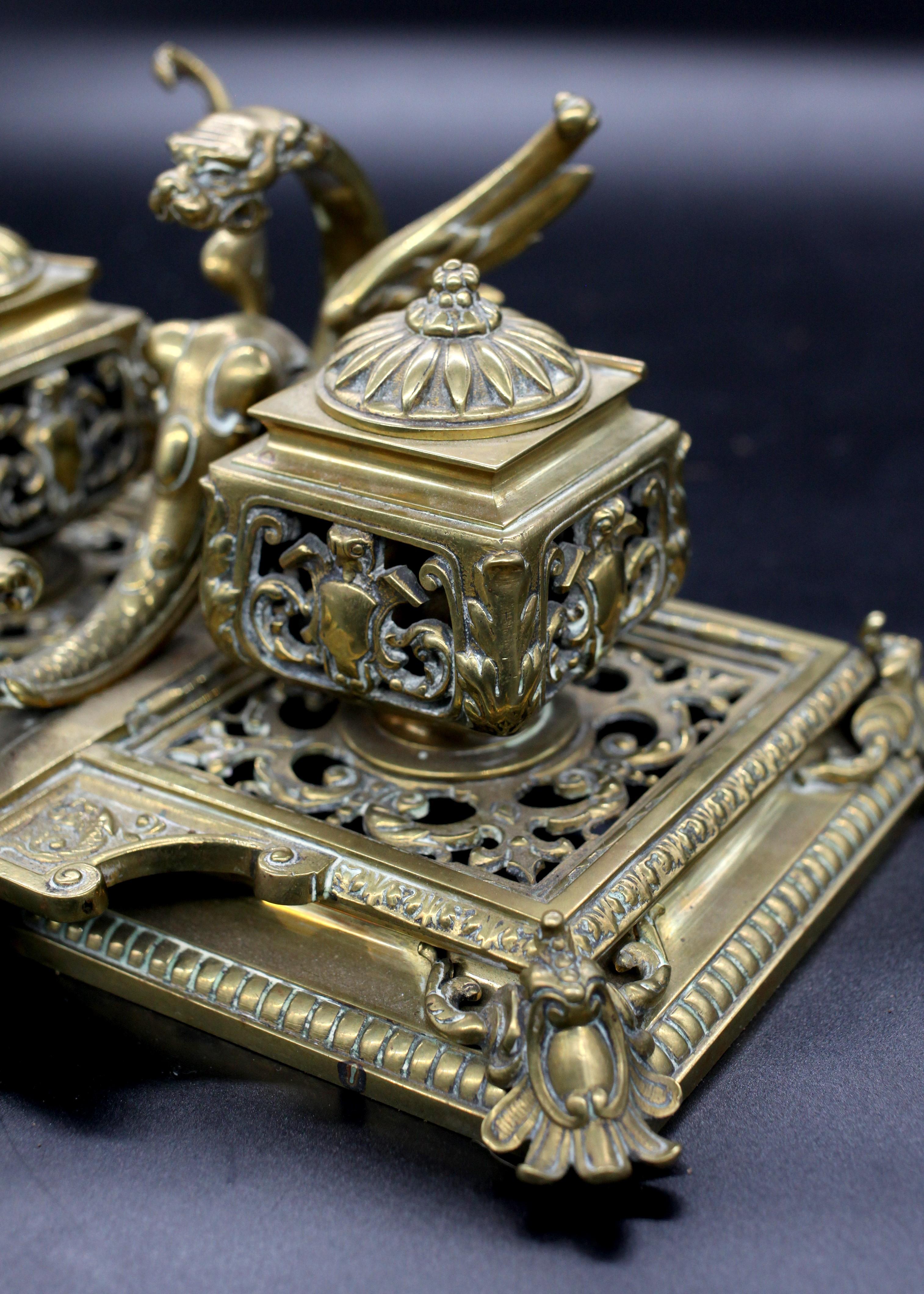 A bewitching blend of form and function, this late 19th-century English Victorian Brass Double Inkwell Desk Stand is a splendid testament to the Victorian era's affinity for detail and grandeur. The stand, carefully crafted from brass, features a