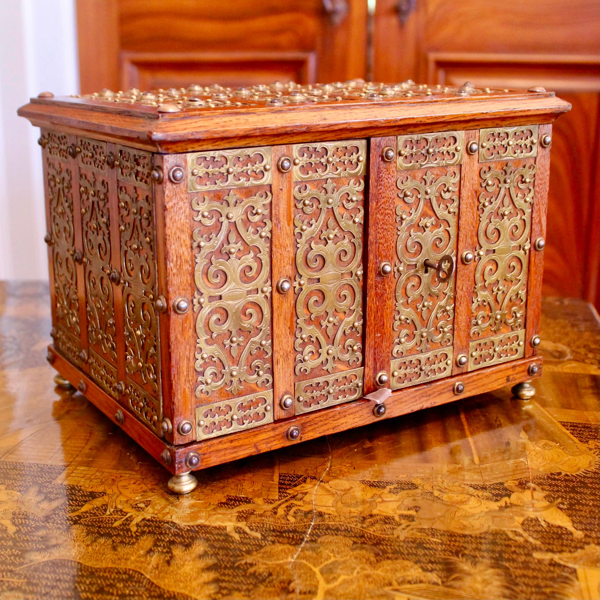 A fine and very decorative Victorian era (late 19th century) jewelry box of quarter sawn oak, designed in the historic tradition of fortified strong boxes, clad in studs and metal strap work panels and fitted with a working lock. The interior