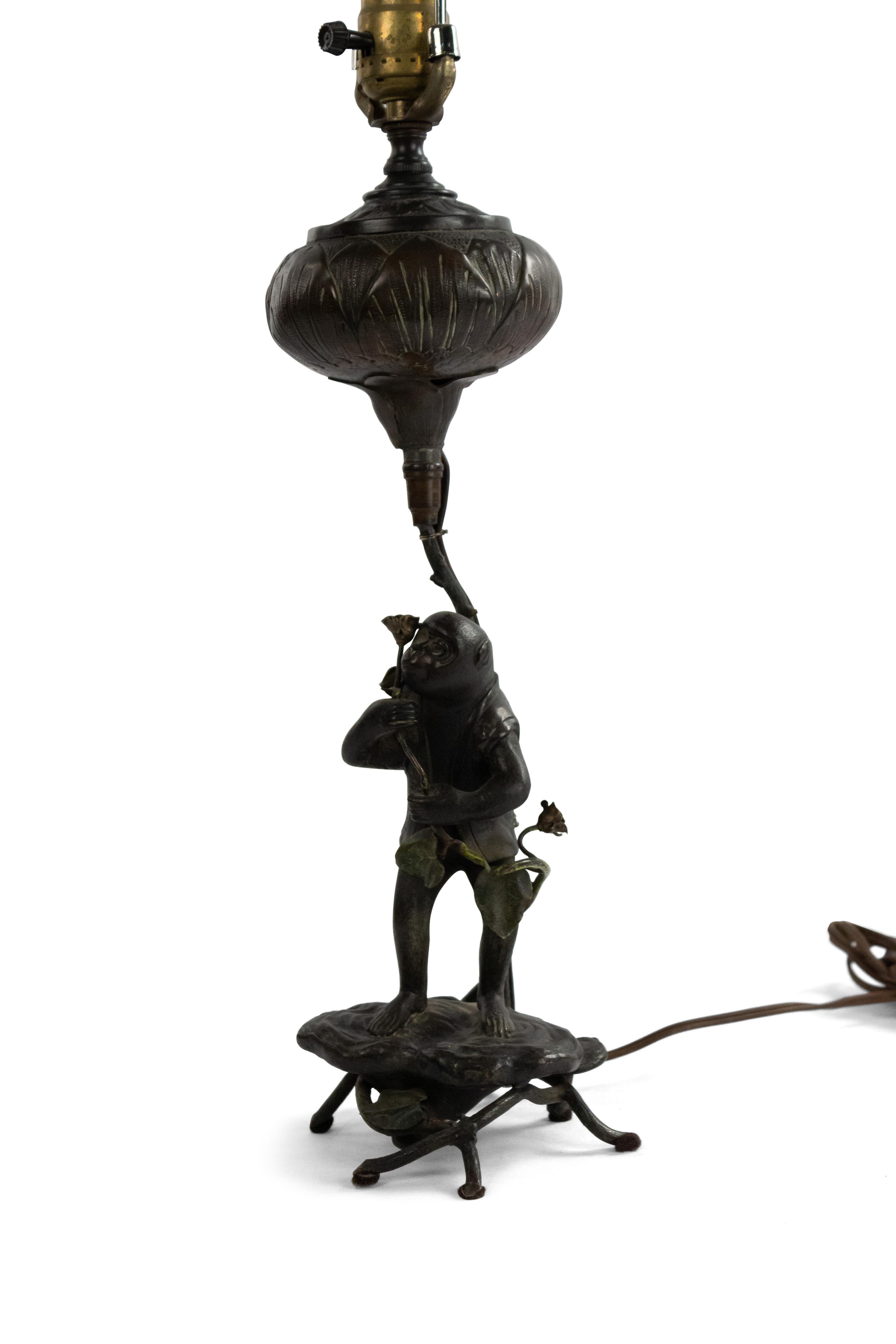 Lampe de table anglaise victorienne en bronze représentant un singe tenant une fleur.
