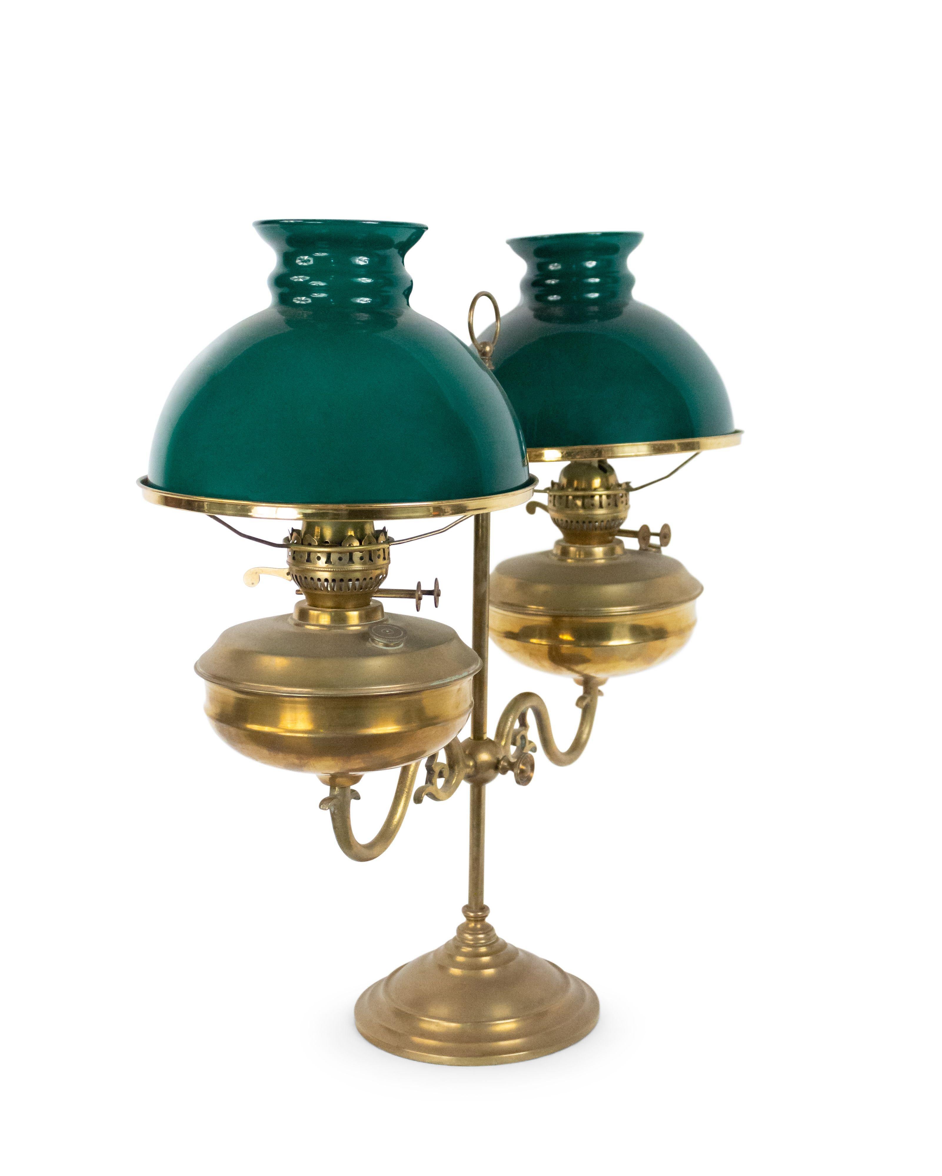 English Victorian style bronze adjustable double arm student lamp with oil font supporting green glass shades.