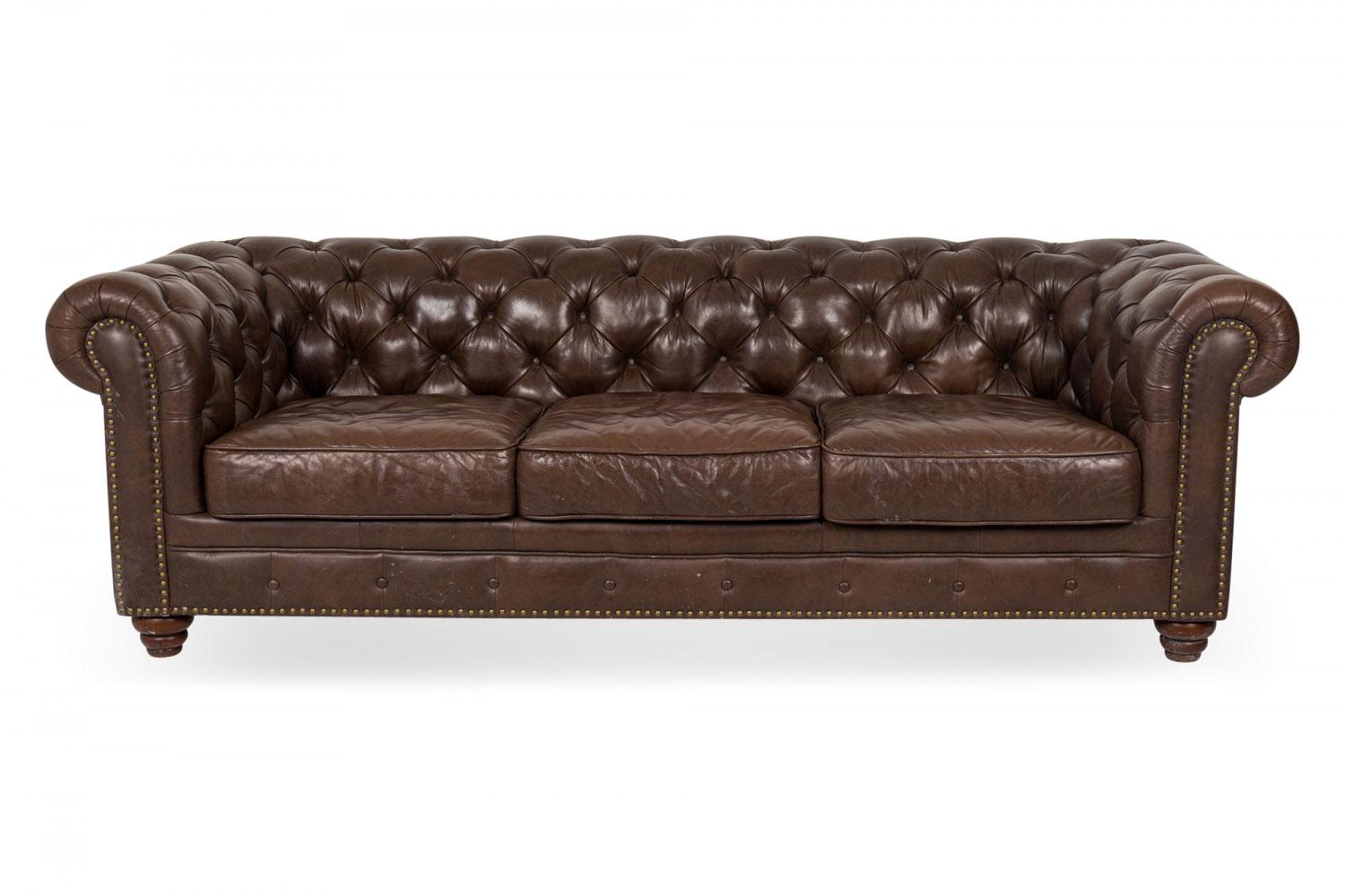 Englisches Chesterfield-Sofa im viktorianischen Stil (20. Jahrhundert) mit drei Sitzen, tiefbraunem, getuftetem Lederbezug, drei abnehmbaren Sitzkissen, Scroll-Armlehnen und antiken Messingnägeln, auf vier konischen Walnussfüßen ruhend.