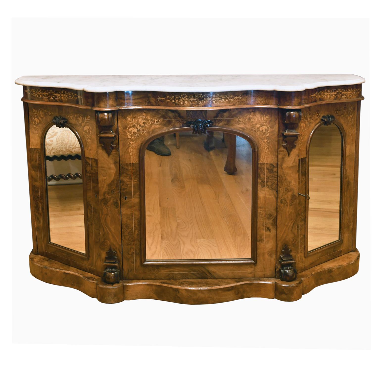 A lovely English Victorian console or credenza in burl walnut with satinwood and kingwood line inlays with original white Carrara marble top. Base offers three cabinet doors with arched mirrored panels that open to storage areas with a fixed shelf
