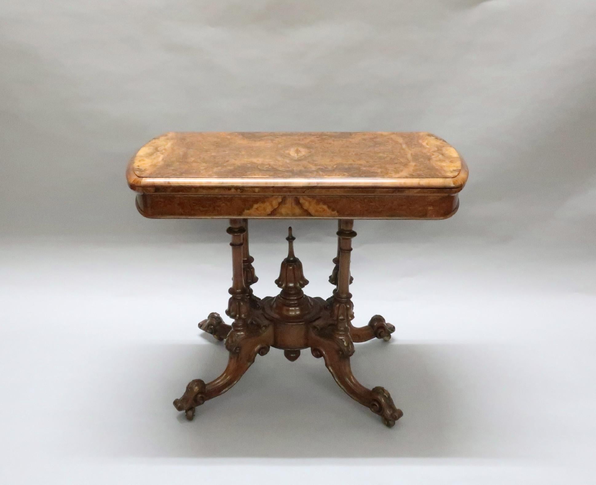 An extremely fine quality Victorian burr walnut fold over games, side or occasional table. The table base is on four turned central columns with tulip flower head carvings to the bottom, the legs are finished with scroll carvings and a central tulip
