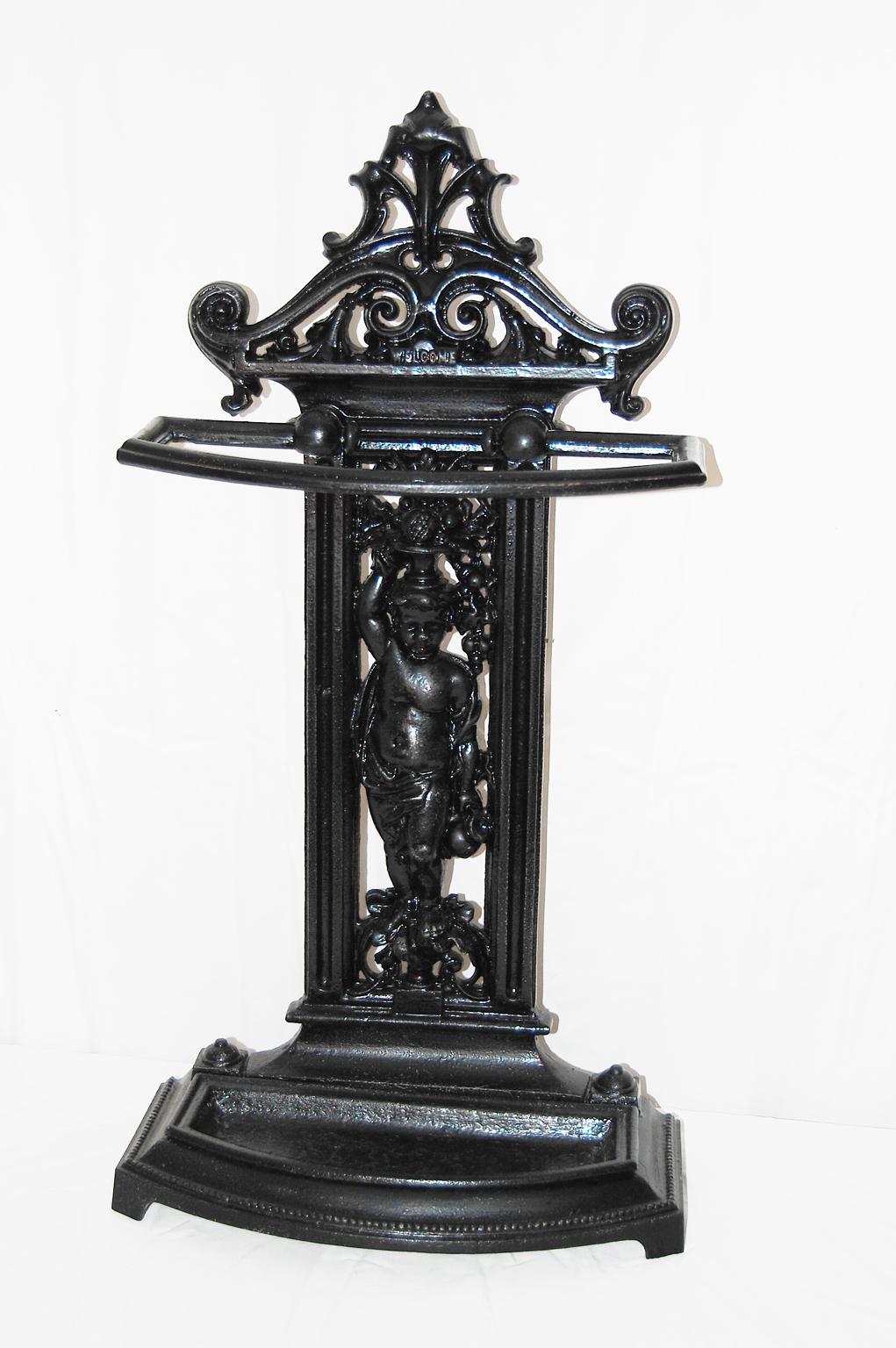 English cast iron Victorian umbrella/stick stand. This stand has a young boy carrying an urn with fruit and flowers on his head as the main decorative motif. The drip pan in the base is removable so it can easily be cleaned. There is a registry date