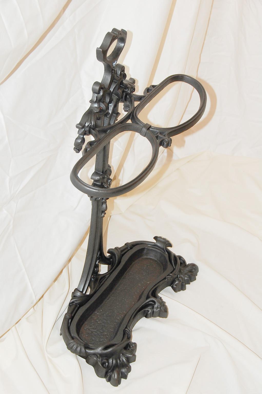 English cast iron victorian umbrella, cane or walking stick stand with separate cast iron drip pan. This substantial stand is crisply cast in iron with leaf and swirl motifs. It is quite heavy so one need not worry about it tipping over, it is very
