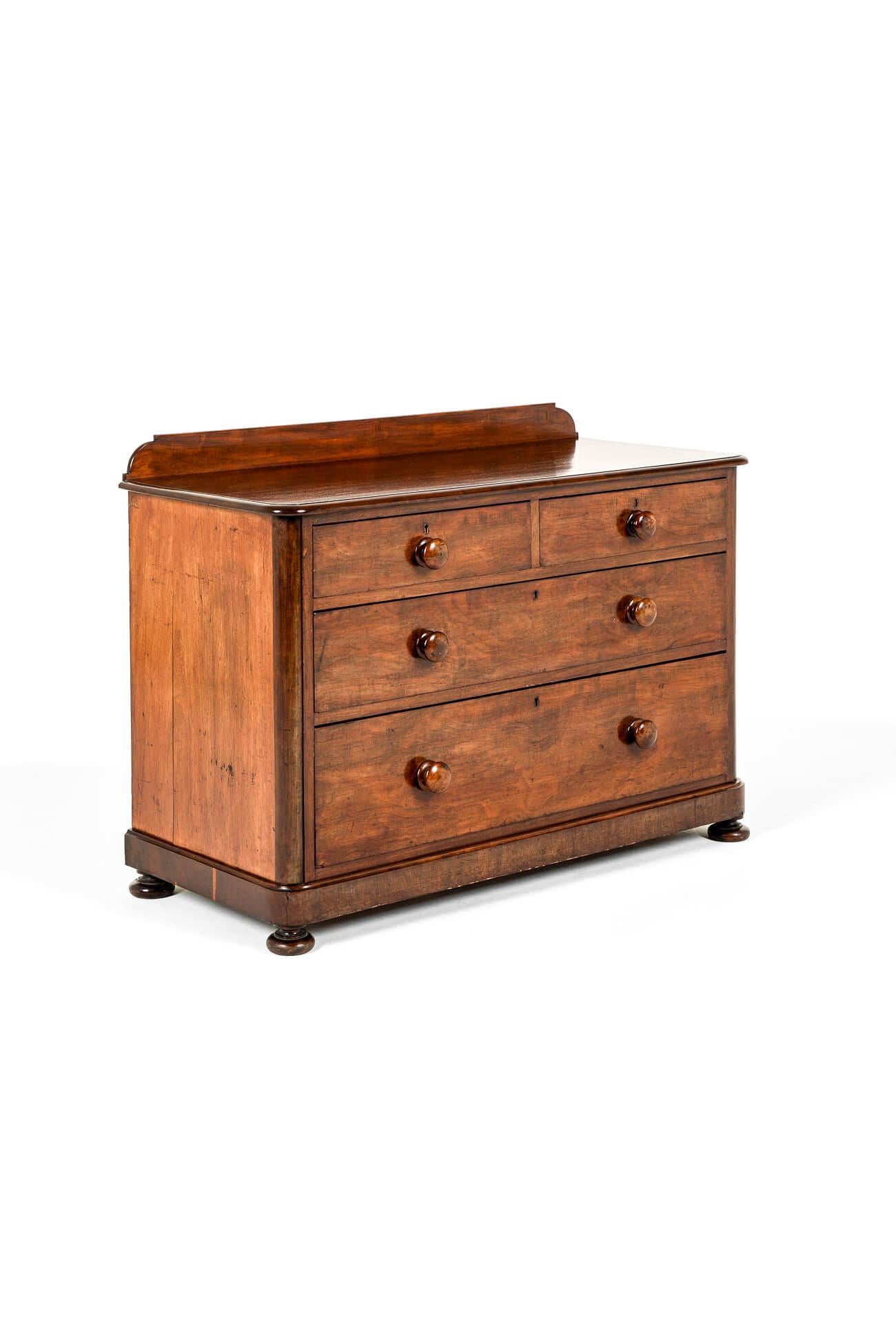 A beautiful low and wide mahogany chest of drawers with a  gently moulded curved top with gallery back.

Two short over two long graduating drawers with original handles below a moulded plinth and raised on low bun feet.

In excellent condition