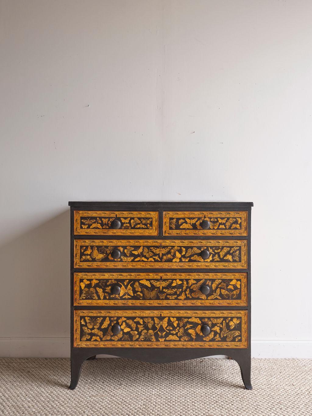 This chest of drawers was built in the Victorian era and displays several different species of butterflies. The butterflies are a light caramel color, and the background color is black. There are two top smaller drawers and three larger bottom