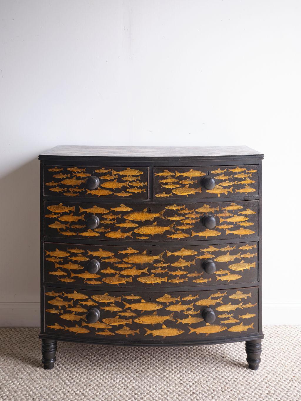 This lovely and unique English Victorian chest of drawers with a fish design would really make a huge statement in any room! The fish have a light caramel color and the background is black. There are two top smaller drawers and three larger bottom
