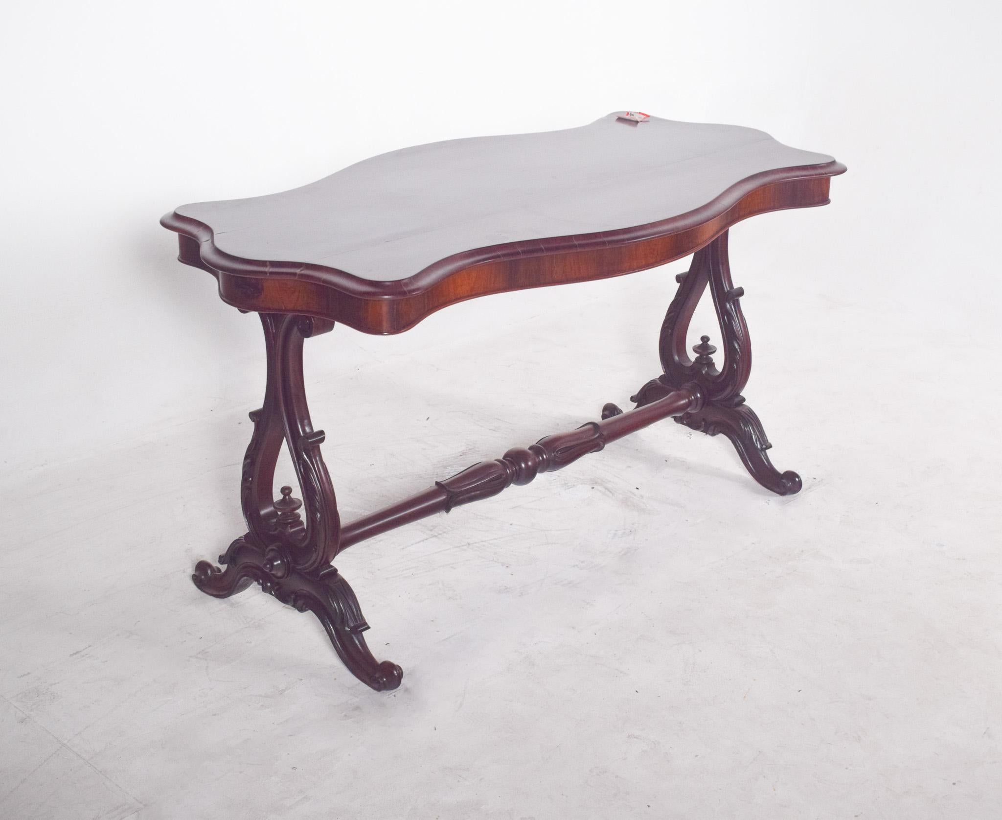 Victorian coffee table in rosewood. The top has jagged, gently rounded contours, revealing the refined craftsmanship typical of furniture from the second half of the 19th century. The dark varnish finish highlights the natural veins of the wood.
The