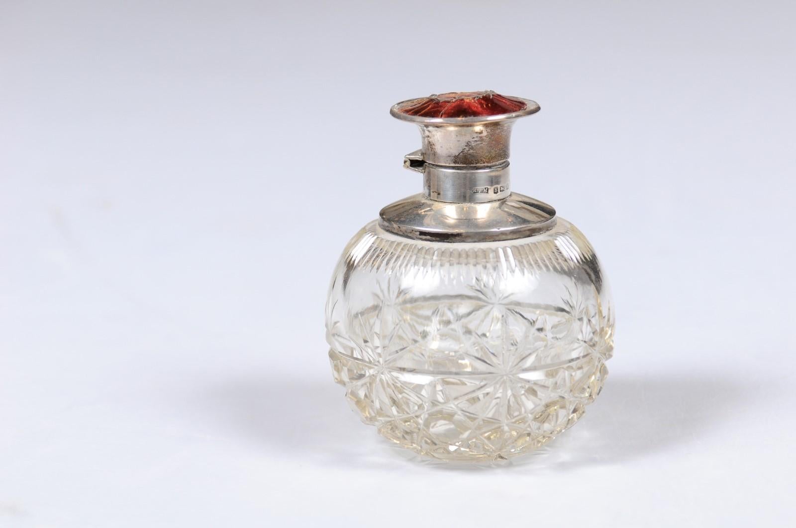 An English crystal toiletry bottle from the 19th century with silver lid and star motifs. Born in England during the reign of Queen Victoria, this elegant crystal toiletry bottle features a circular body, adorned with a delicate star-shaped décor.