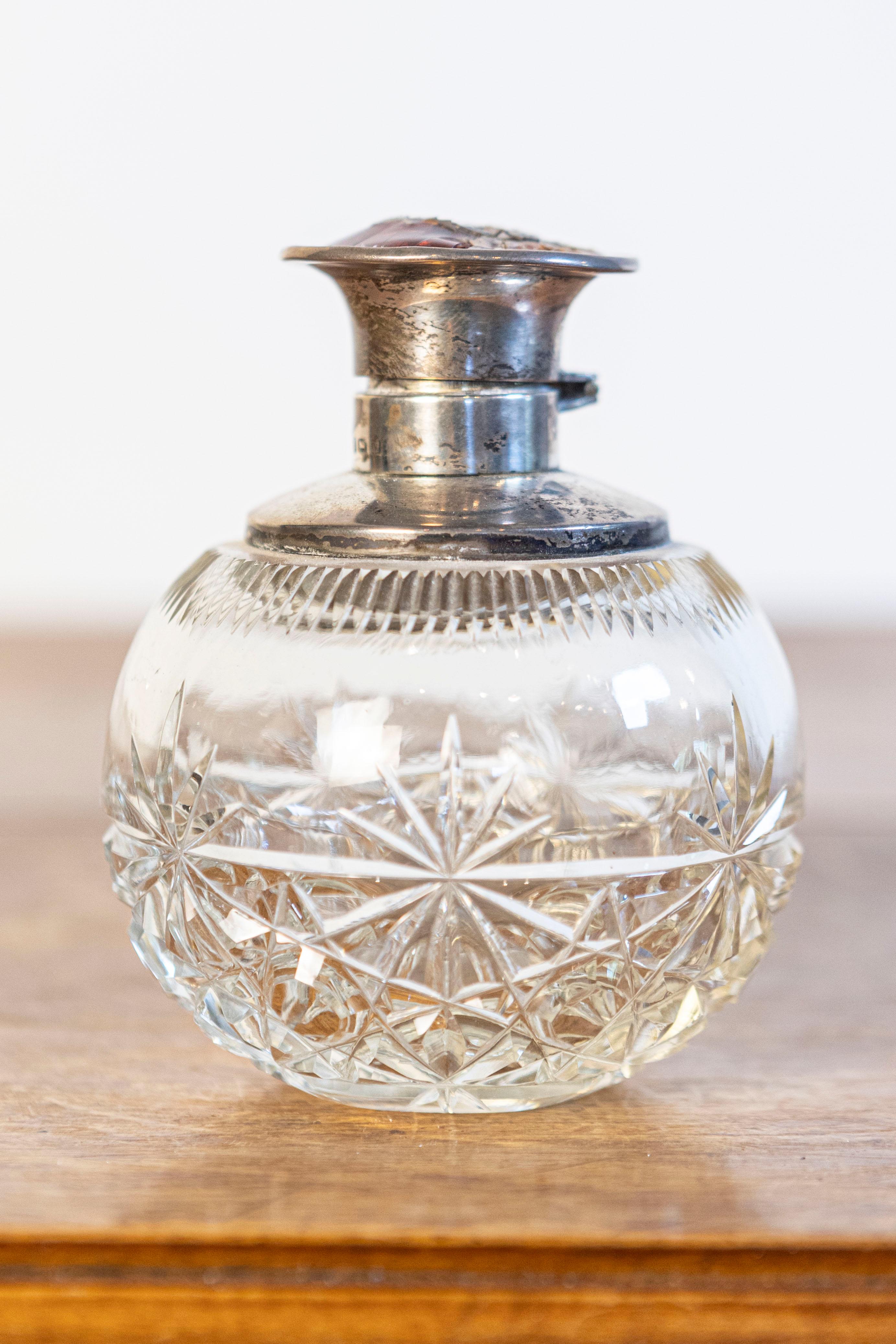 An English crystal toiletry bottle from the 19th century with silver lid and star motifs. Born in England during the reign of Queen Victoria, this elegant crystal toiletry bottle features a circular body, adorned with a delicate star-shaped décor.