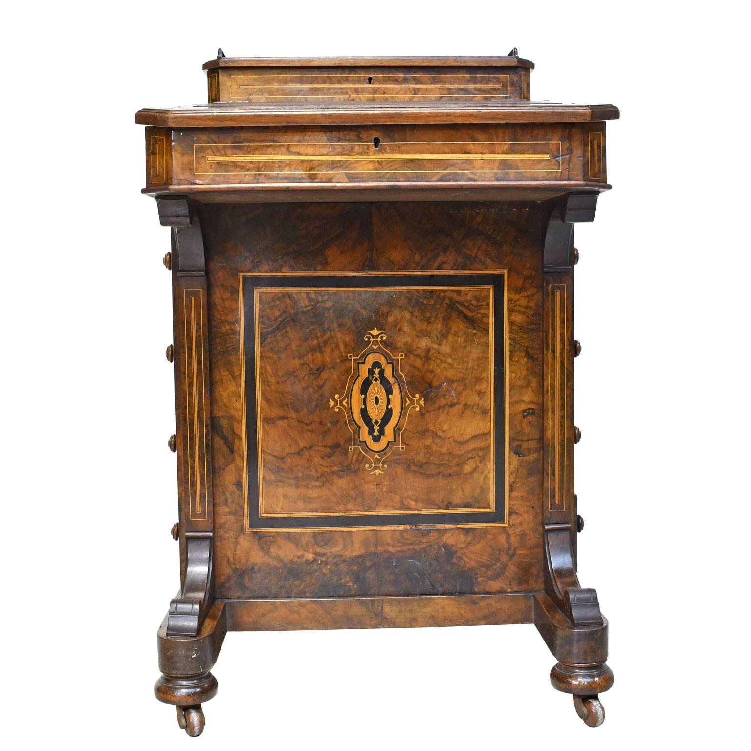 A handsome English Victorian Davenport desk in burled and solid walnut with beautiful inlays in ebonized wood, kingwood and tulipwood. Has original inset brown leather with gold tooling on writing surface, and two glass inkwells and a few pen nibs.