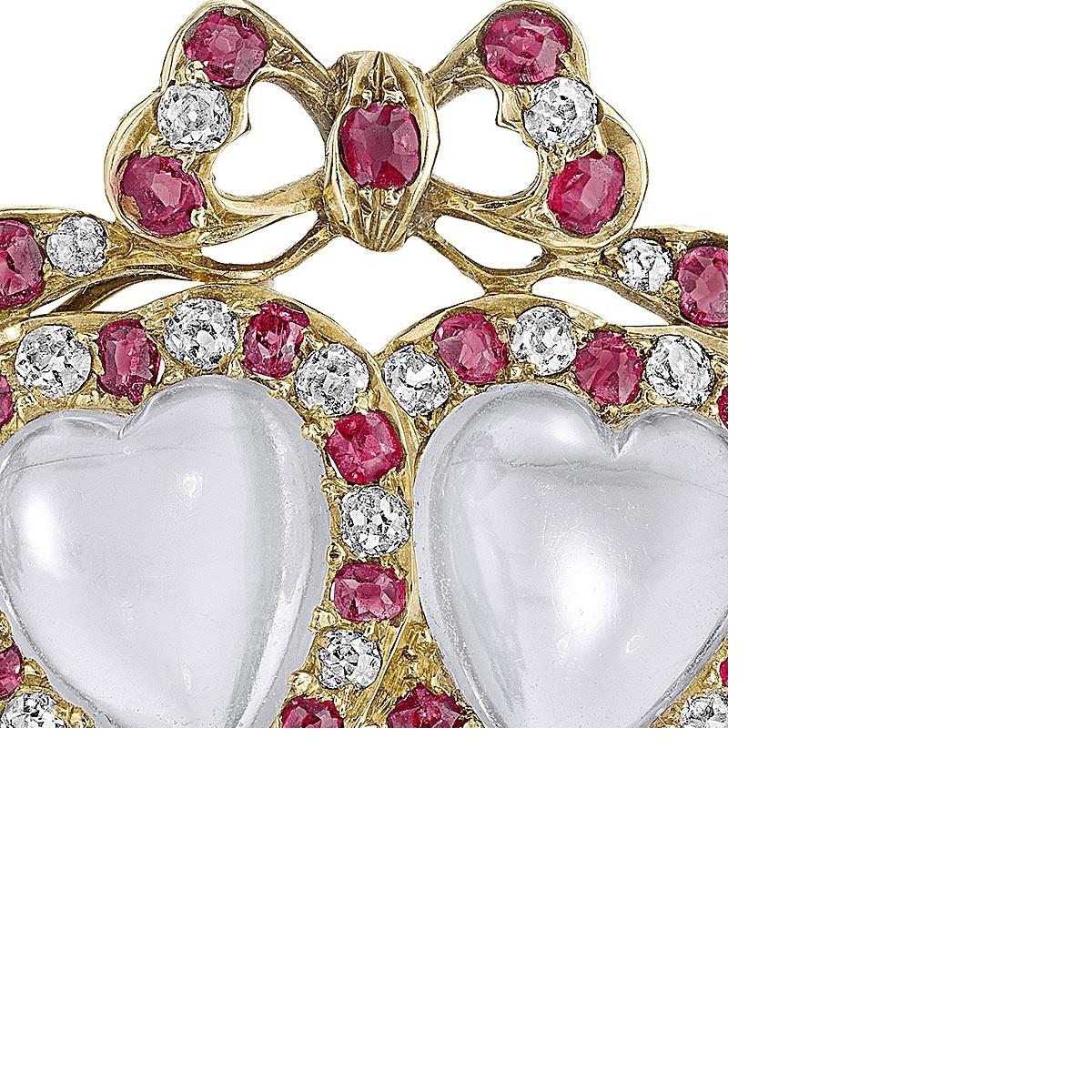 A Victorian 15 karat gold brooch with moonstones, diamonds and rubies. The coupled heart-shaped moonstones are each framed by a bright ring of alternating round-cut diamonds and rubies, and topped with a flowing diamond and ruby ribbon tied in a
