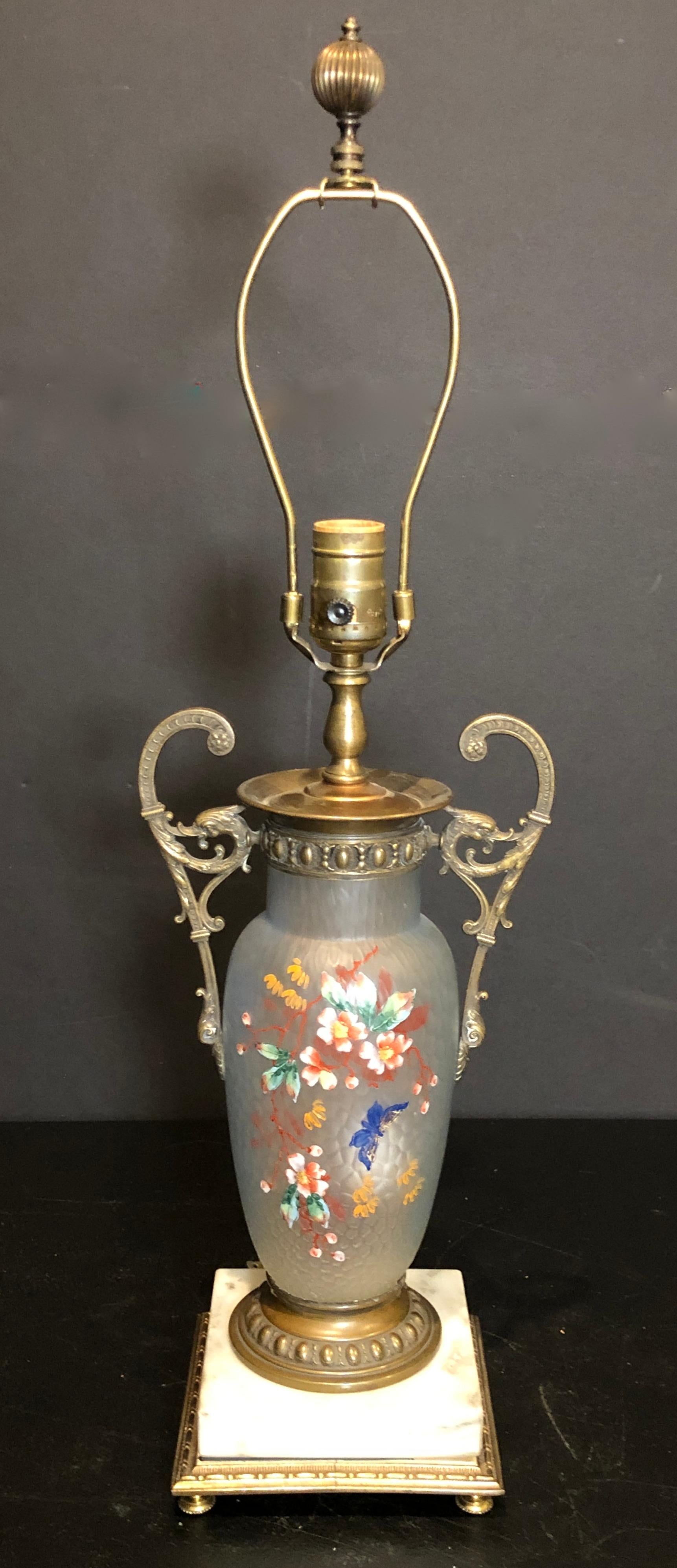 Enameled bronze mounted glass vase as lamp. English Victorian chinoiserie enameled florals with butterfly. Colorful enamel on clear satin textured glass. Bronze handles with griffin heads. White marble base.
14